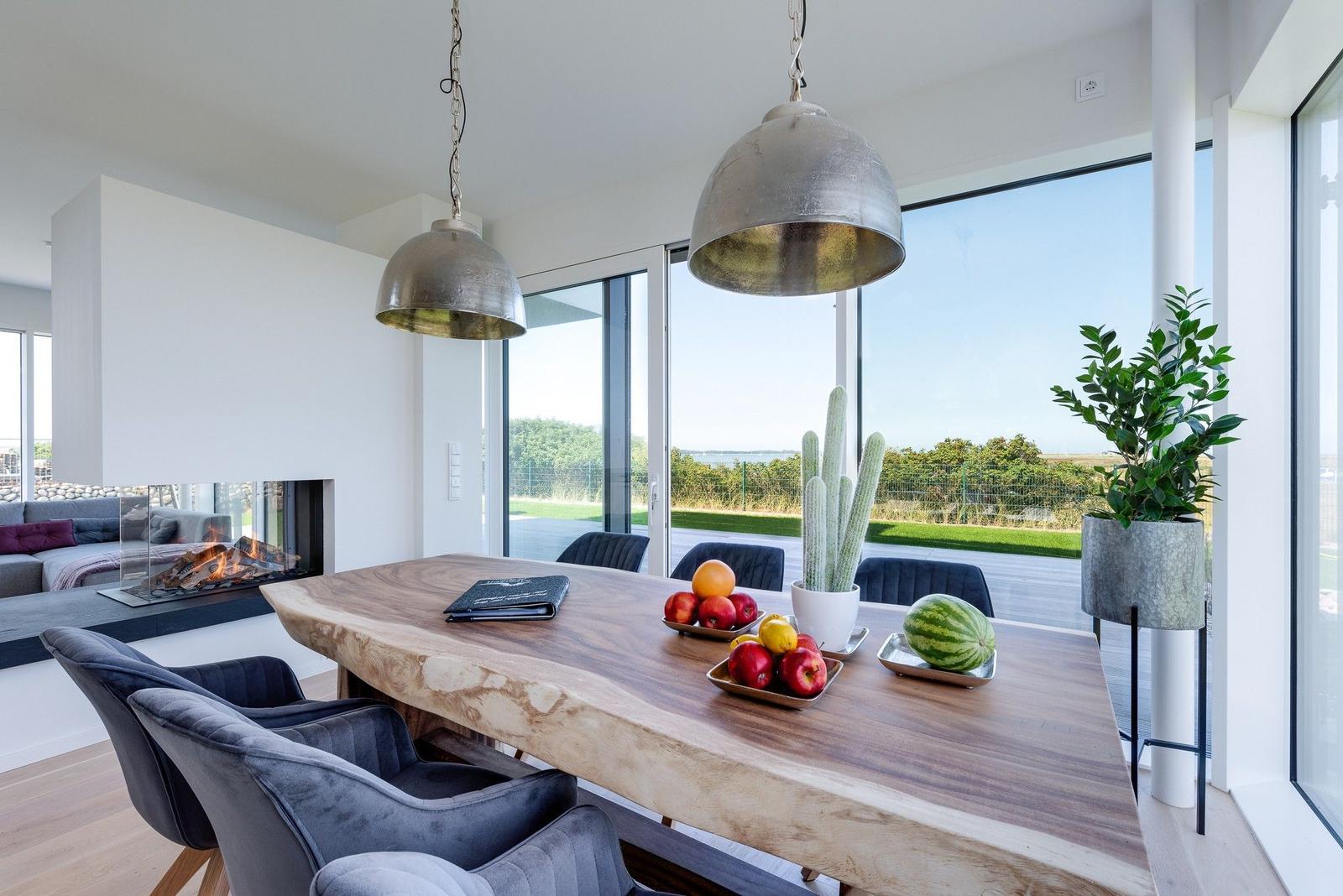 Essbereich mit Holztisch, Stühlen und Blick auf die Landschaft.