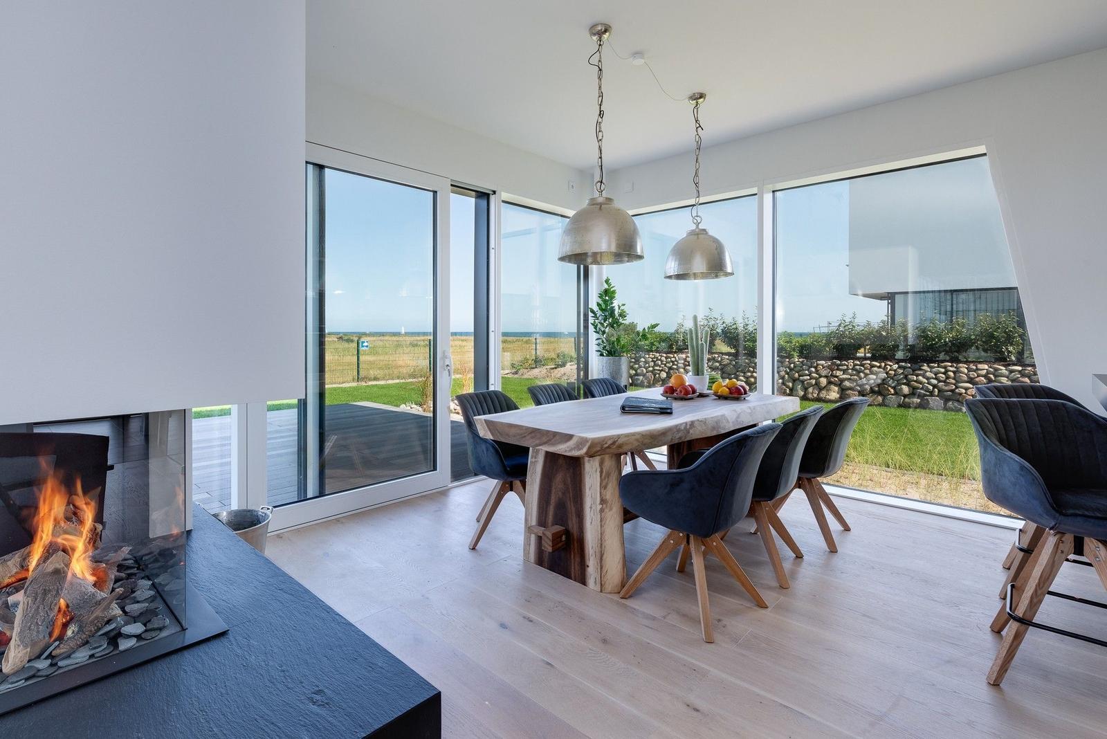 Essbereich mit Holztisch, dunklen Stühlen und Blick auf Grünland.