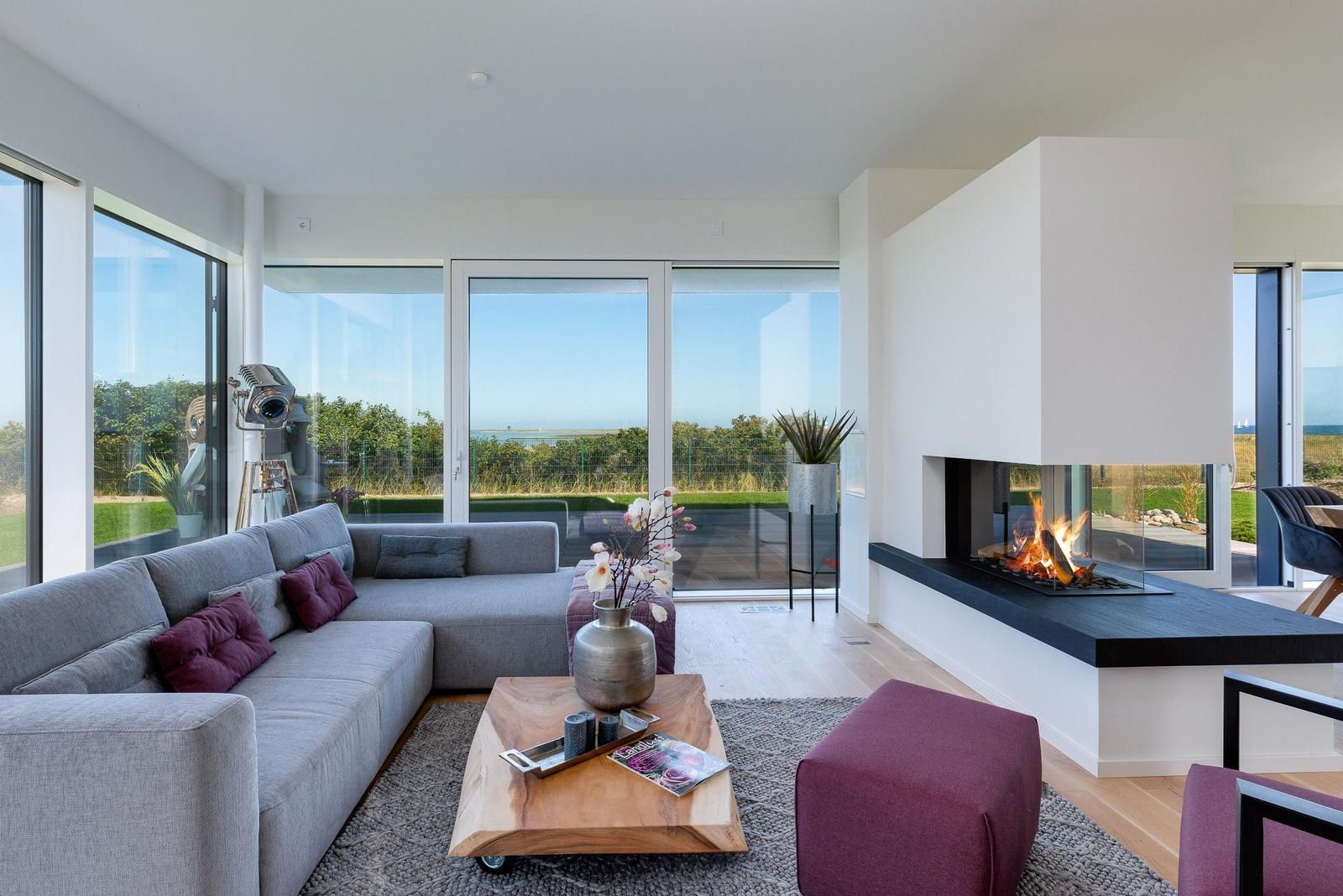 Wohnzimmer mit Sofa, Kamin und Blick auf den Garten