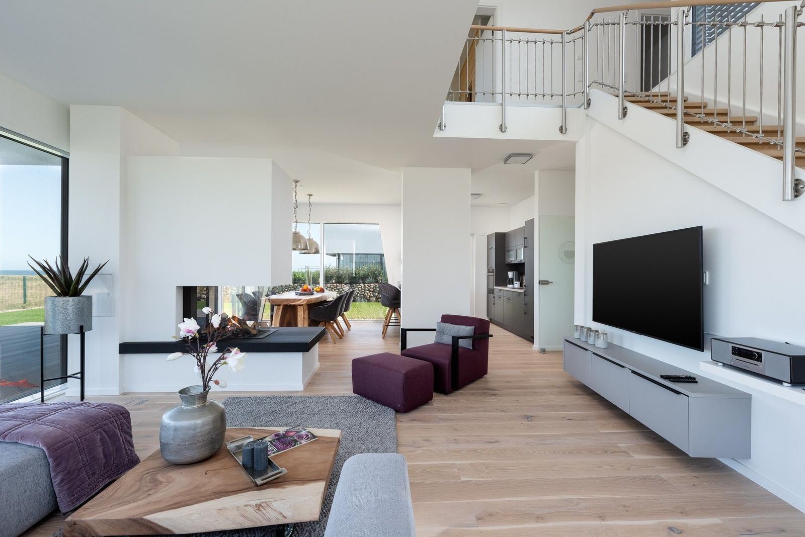 Wohnbereich mit Kamin, TV und Balkonzugang. Holzboden und moderne Einrichtung.