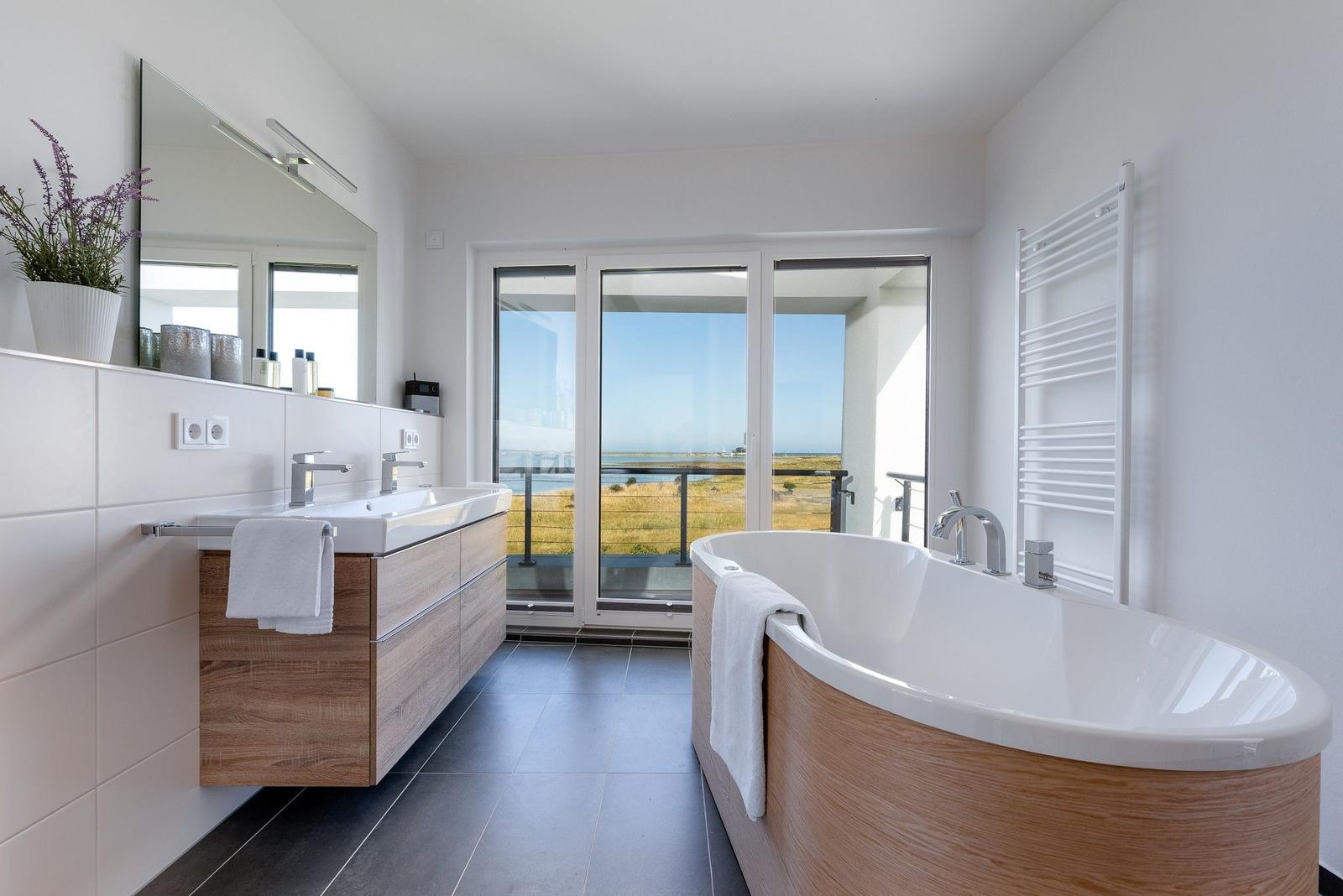 Badezimmer mit Badewanne und Dusche, Blick auf Balkon und Meer.