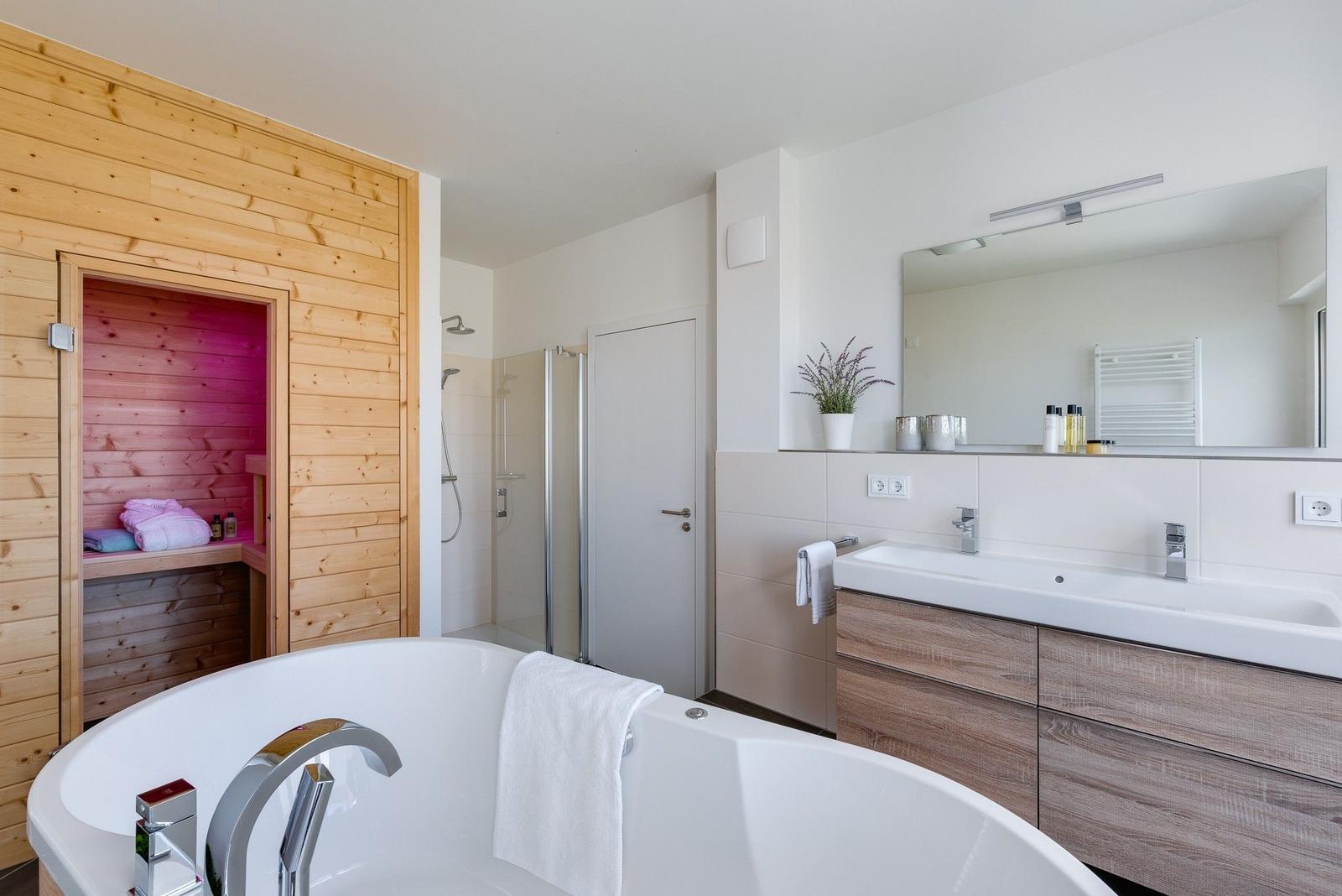 Bad mit Whirlpool, Dusche und Sauna. Holzwände und Waschtisch mit Spiegel.