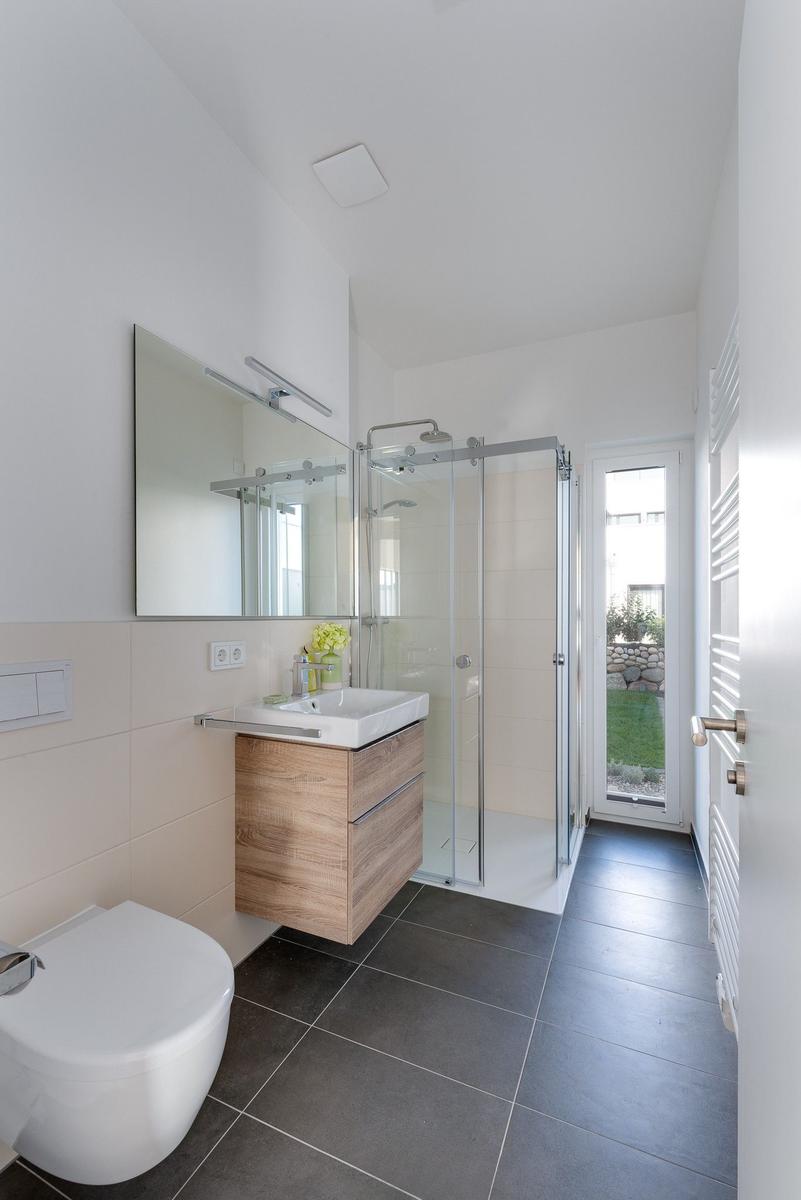 Badezimmer mit Dusche, Waschbecken und Toilette. Durchgang zur Terrasse.