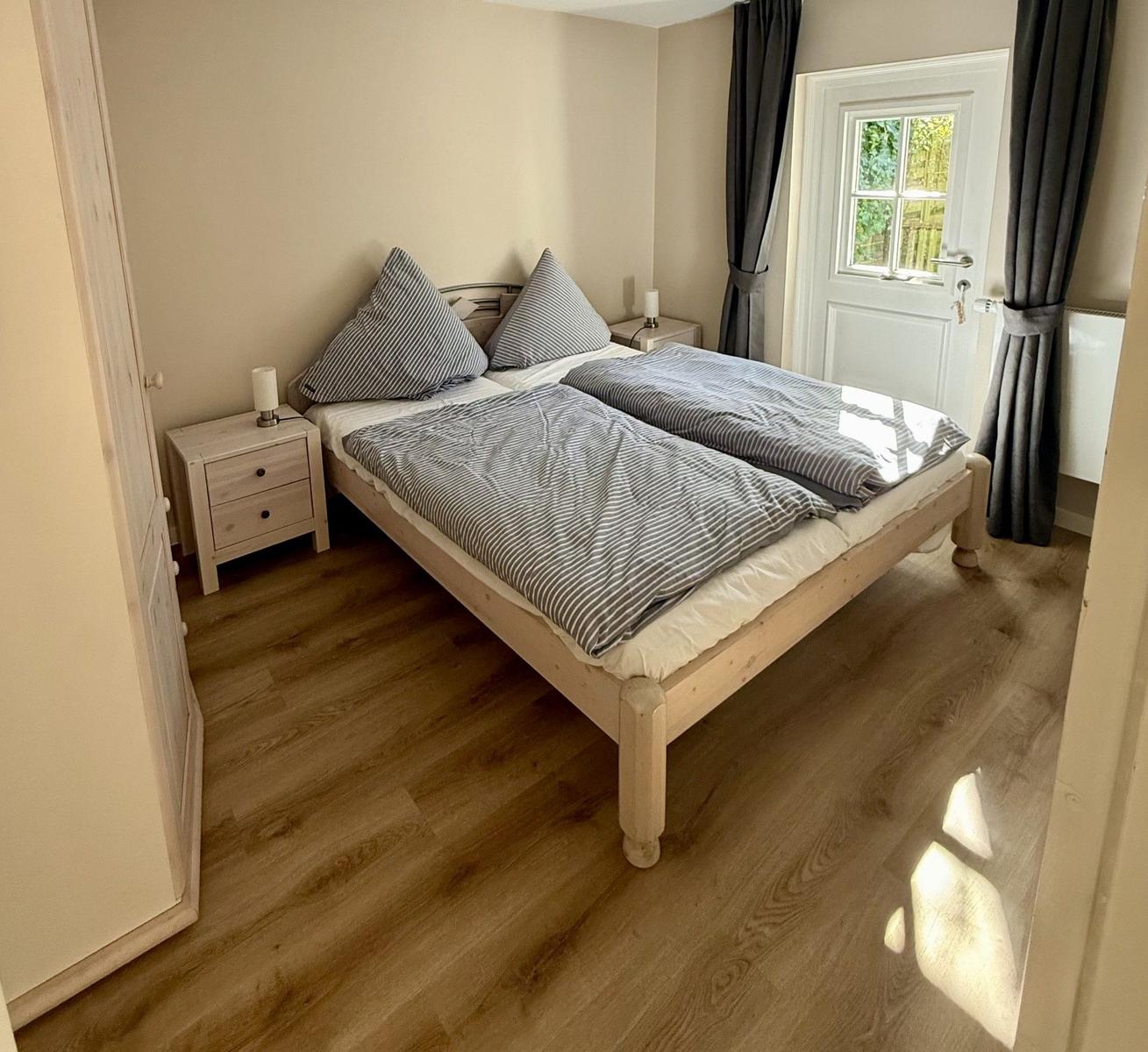 Schlafzimmer mit Doppelbett, Nachttischen und Fenster mit Vorhängen.