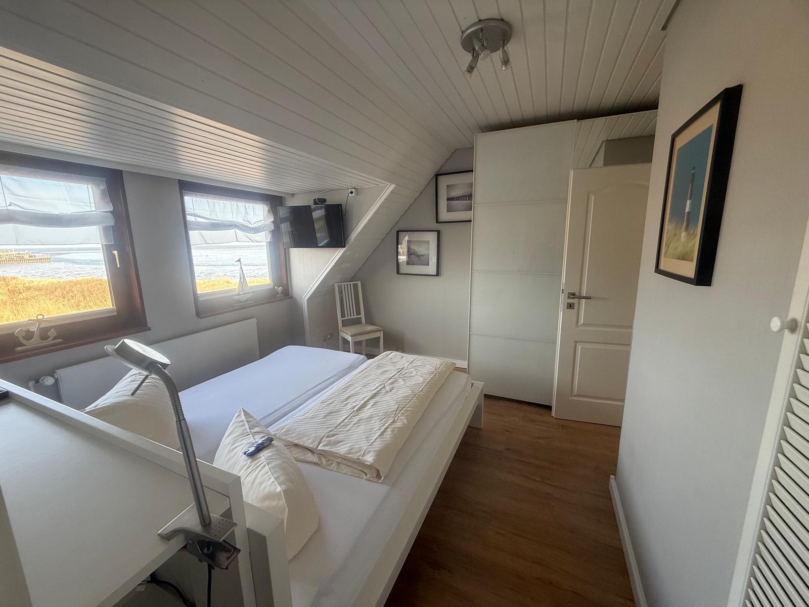 Schlafzimmer mit Blick auf Wasser, Bett, Fernseher und Wandbild