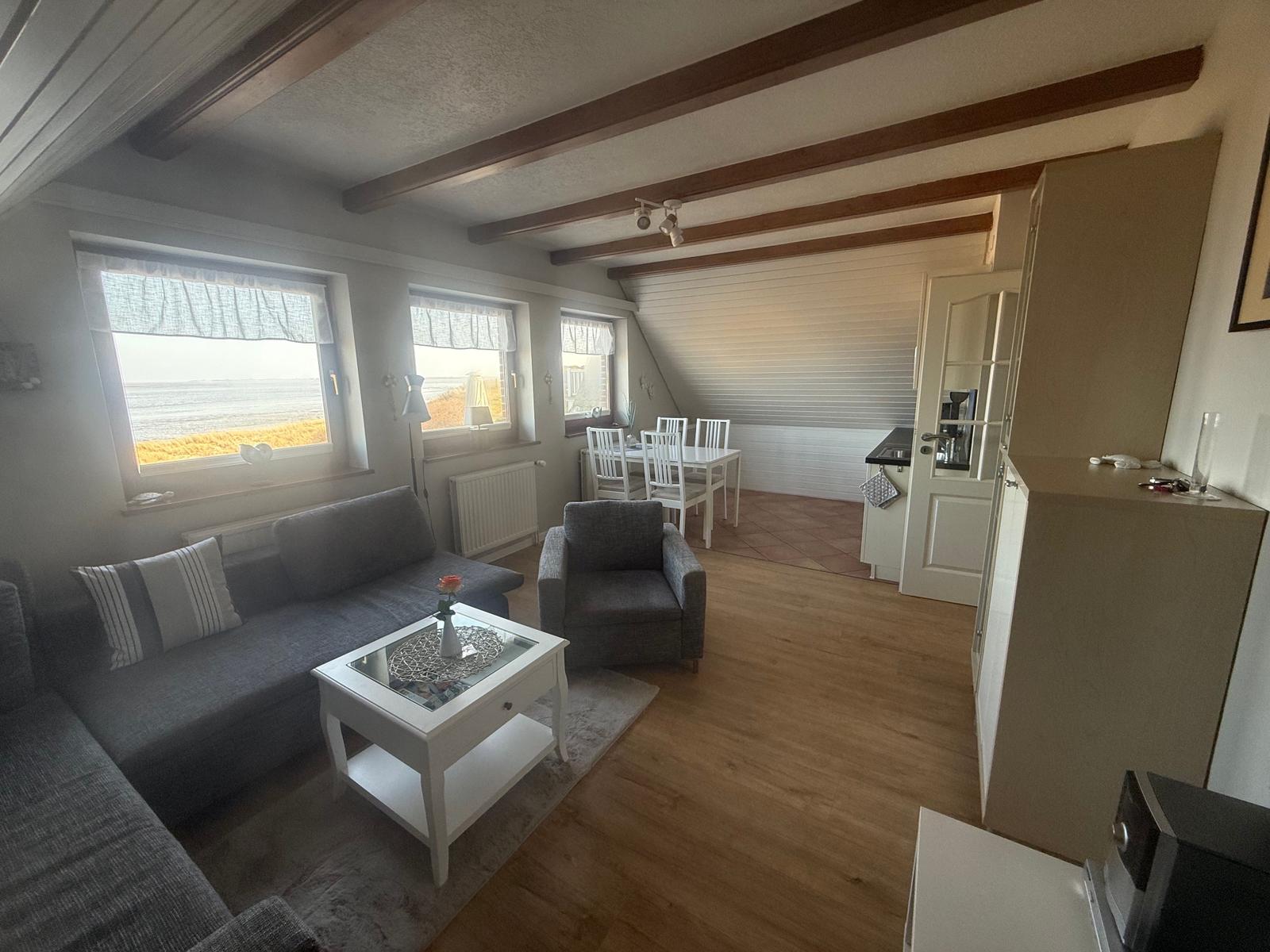 Wohnzimmer mit Sofa, Sessel und Küchenbereich. Fenster mit Meerblick.