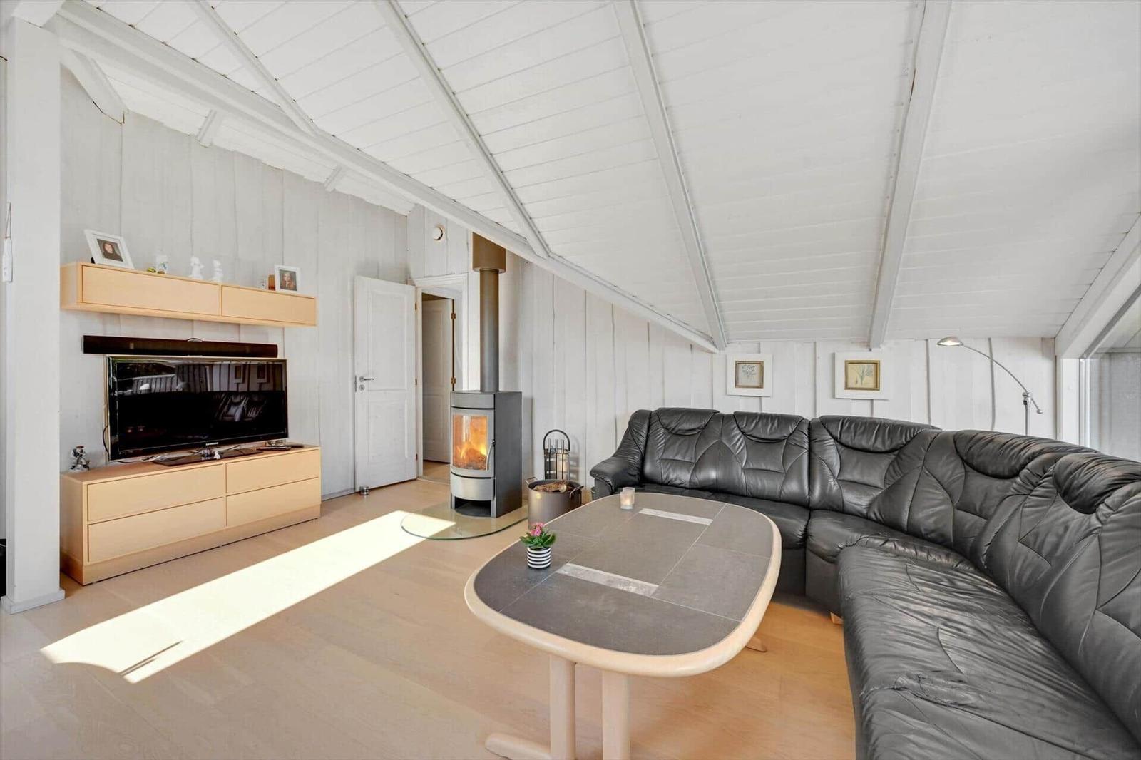 Living room with sofa, fireplace, and TV mounted on the wall.