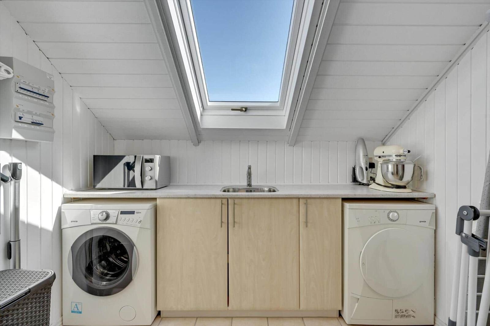 Kitchen with washing machine, dryer, sink, and skylight.