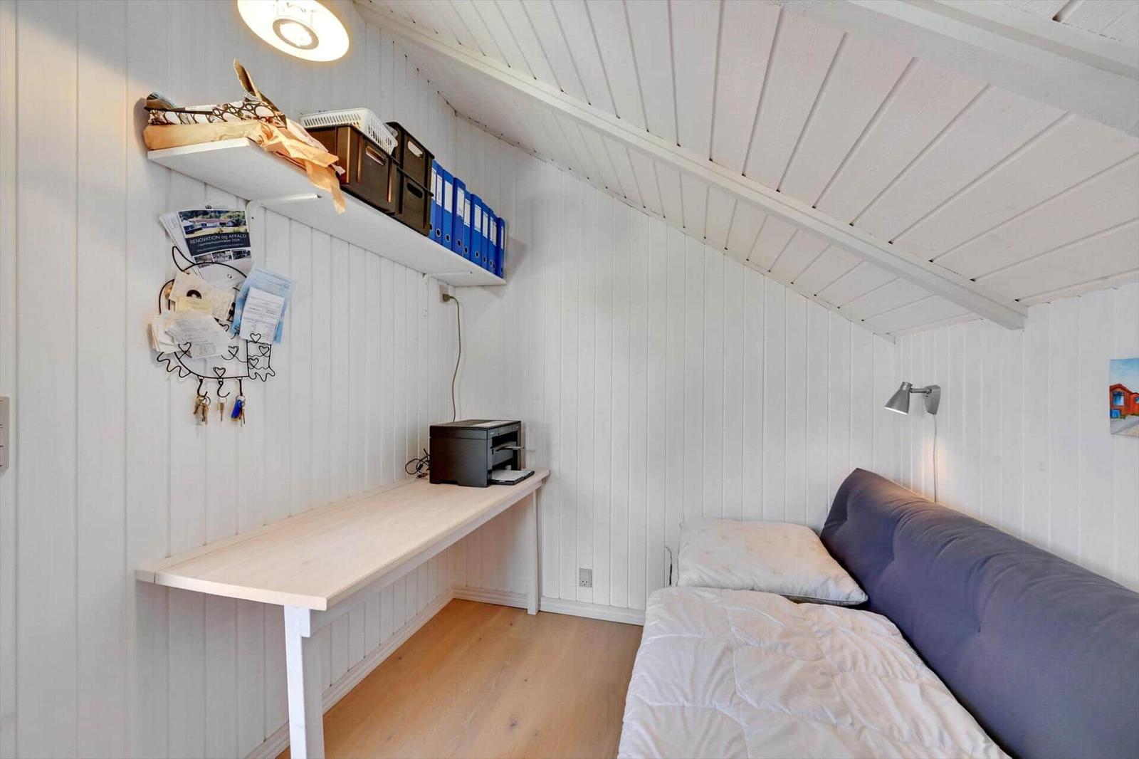 Bedroom with desk, bed, and shelf on the wall.