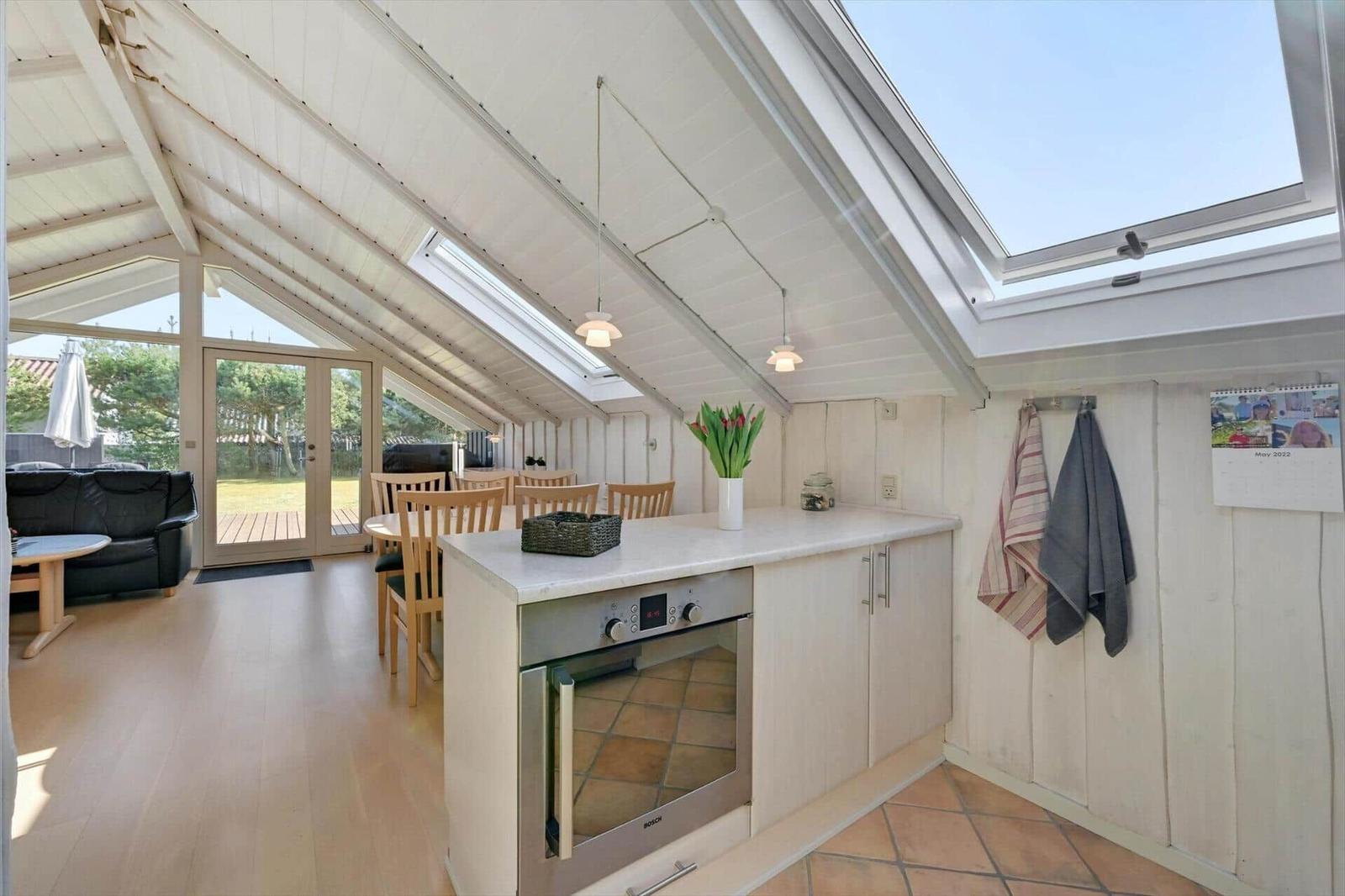 Kitchen with dining area under roof with large skylight and view of garden.
