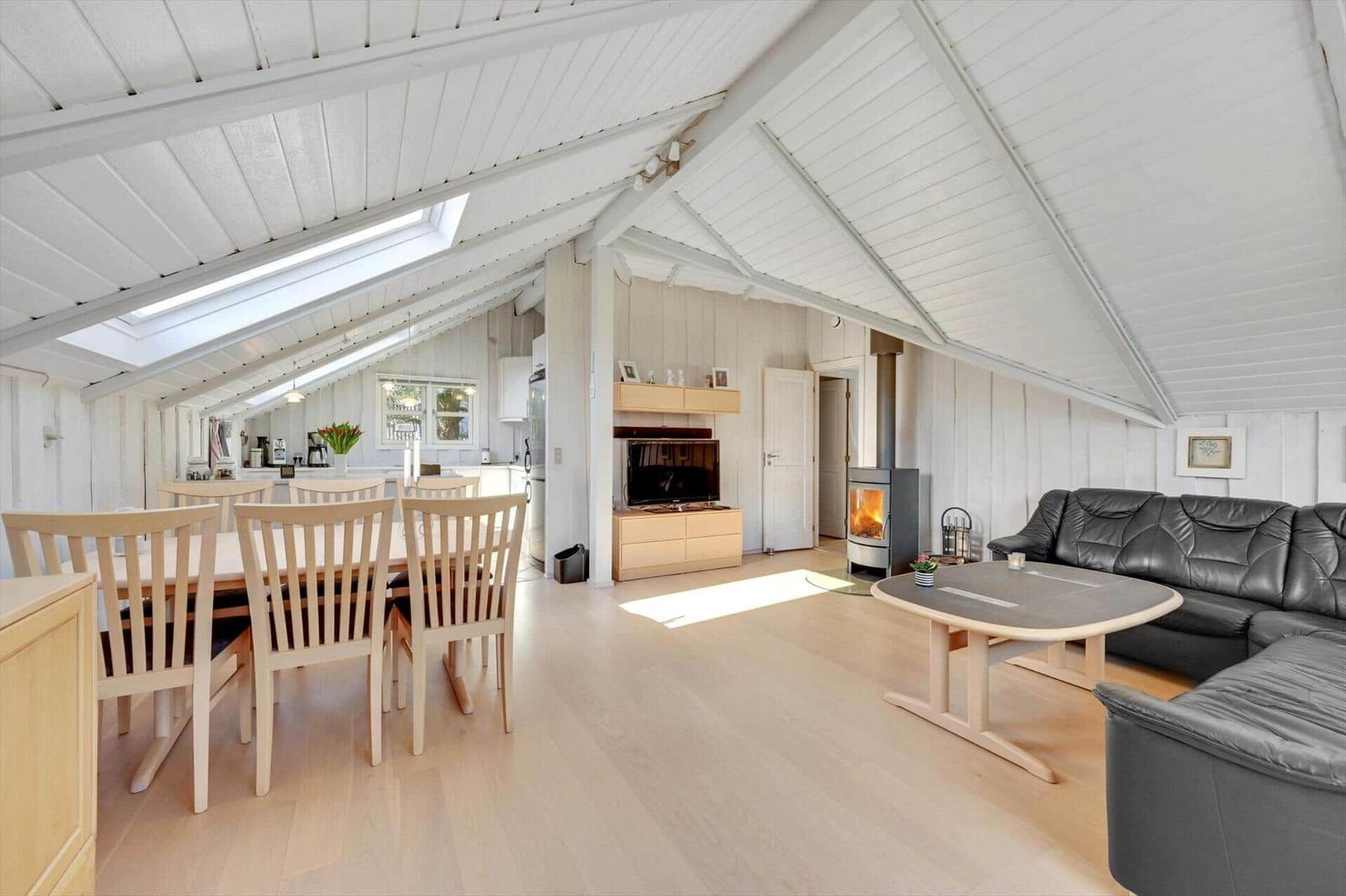 Living and dining area with wooden ceiling, fireplace, and dining table with chairs.
