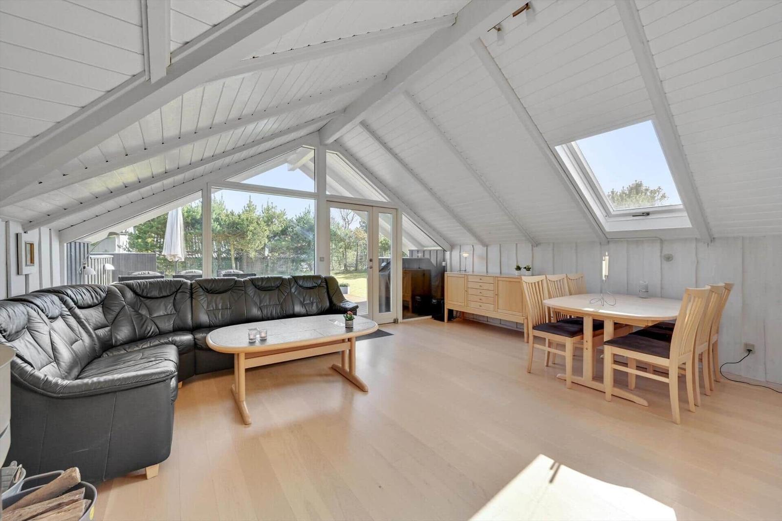 Living and dining area with sofa, table, and windows to the garden.