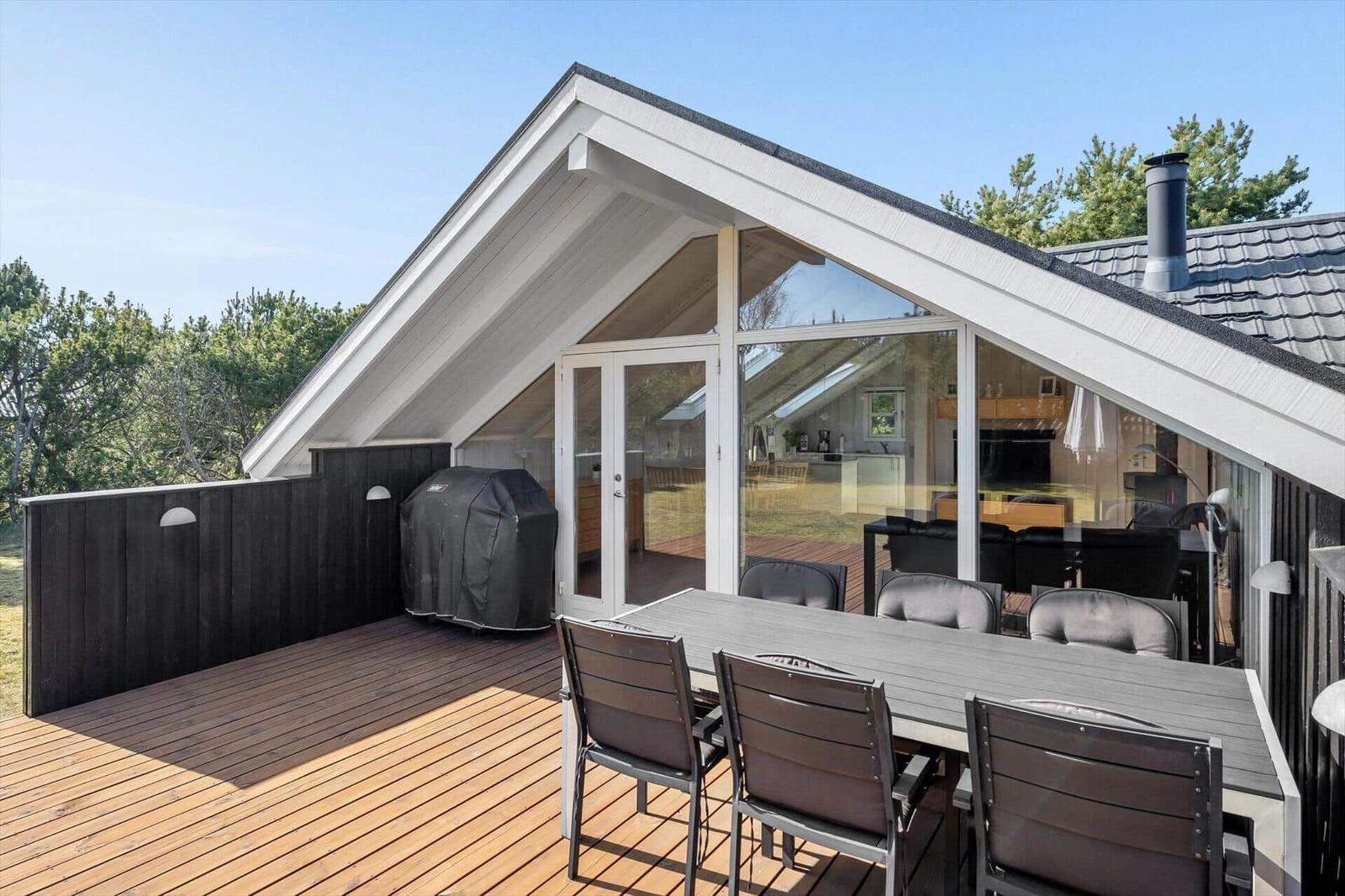 Deck with table and chairs, grill, and view into the house.