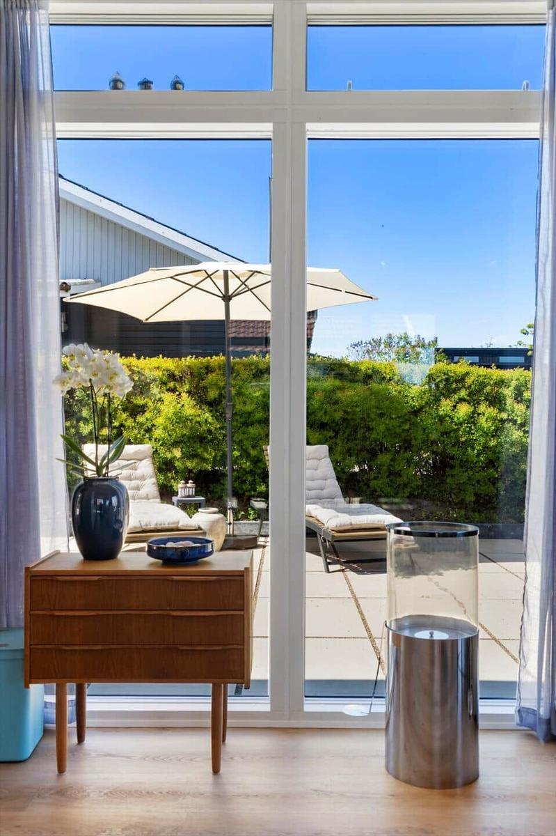 Through large windows, a terrace with loungers and umbrella is visible.