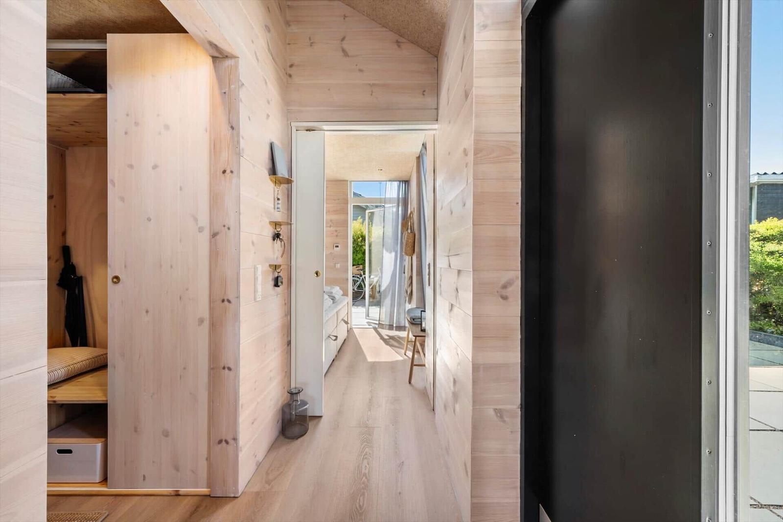 Hallway with wooden walls, closet, and view into living area.