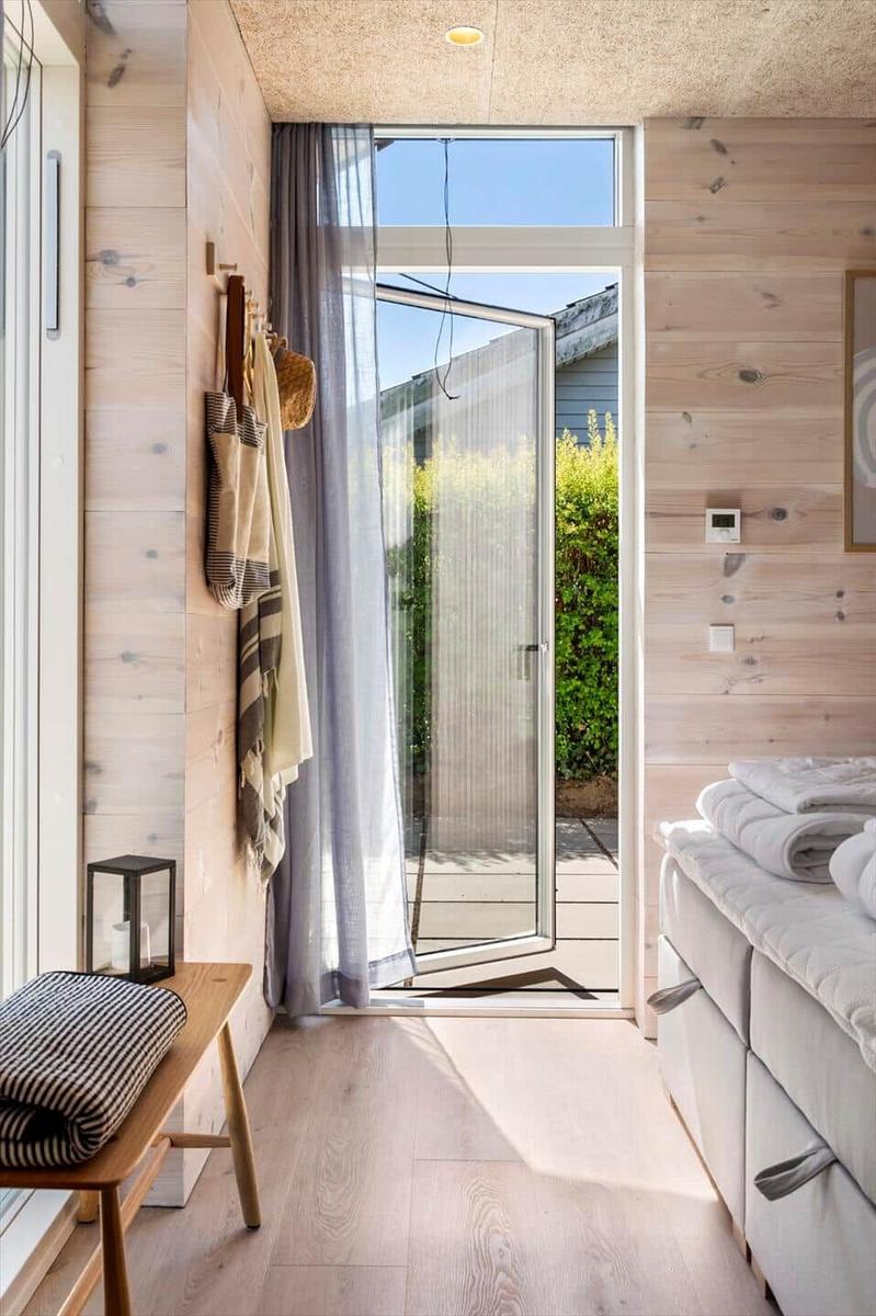 Bedroom with wooden wall, bed, and door to balcony.