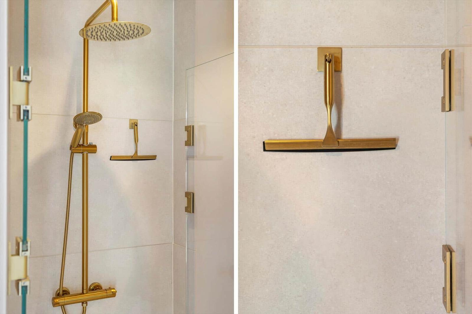 Shower cabin with gold fixtures and glass wall.