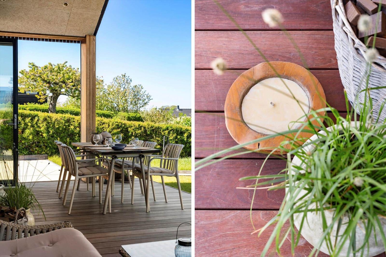 Terrace with table and chairs, view of green hedge and tree. Wooden tray and plant on deck floor.