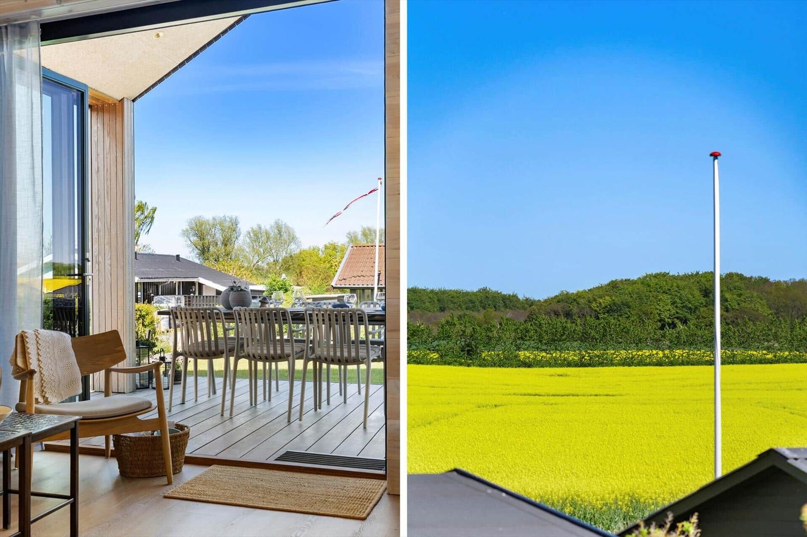 Terrace with table and chairs. View of yellow flower field and green trees.