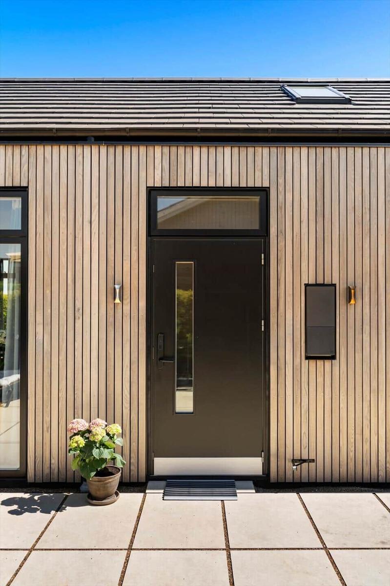 Entrance door with glass panel and wooden facade. A potted plant stands in front.