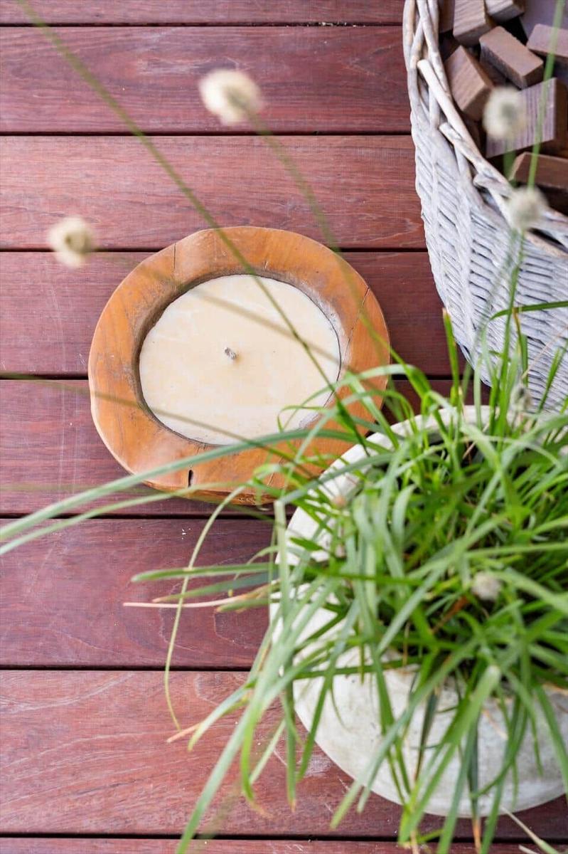 Wooden tray with candle, basket, and plant on wooden deck