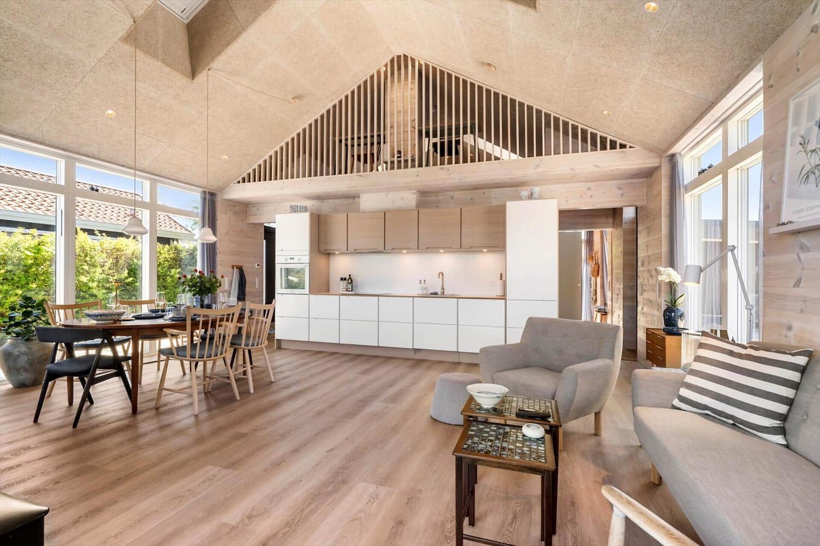 Living area with dining space, kitchen, and balcony. Wooden ceiling and floor.