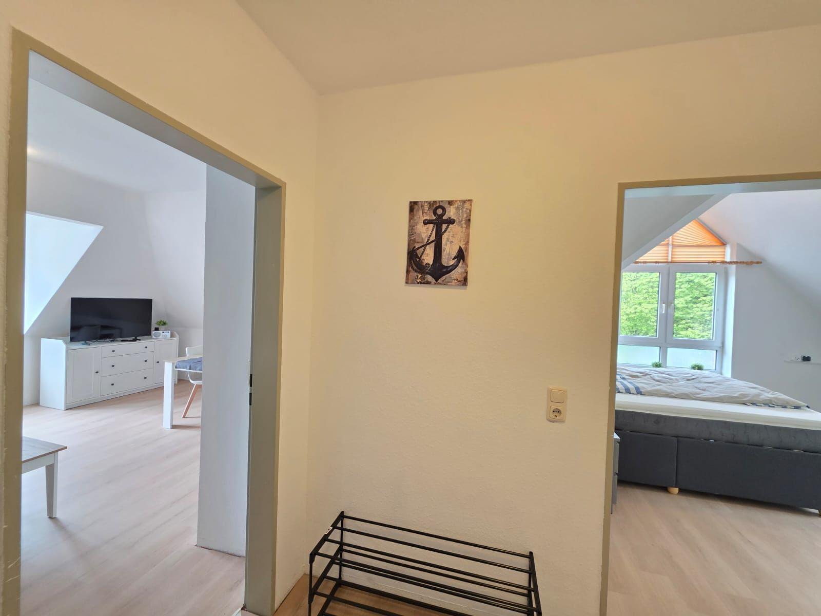 Hallway with view into bedroom and living area. Wall art with anchor design.