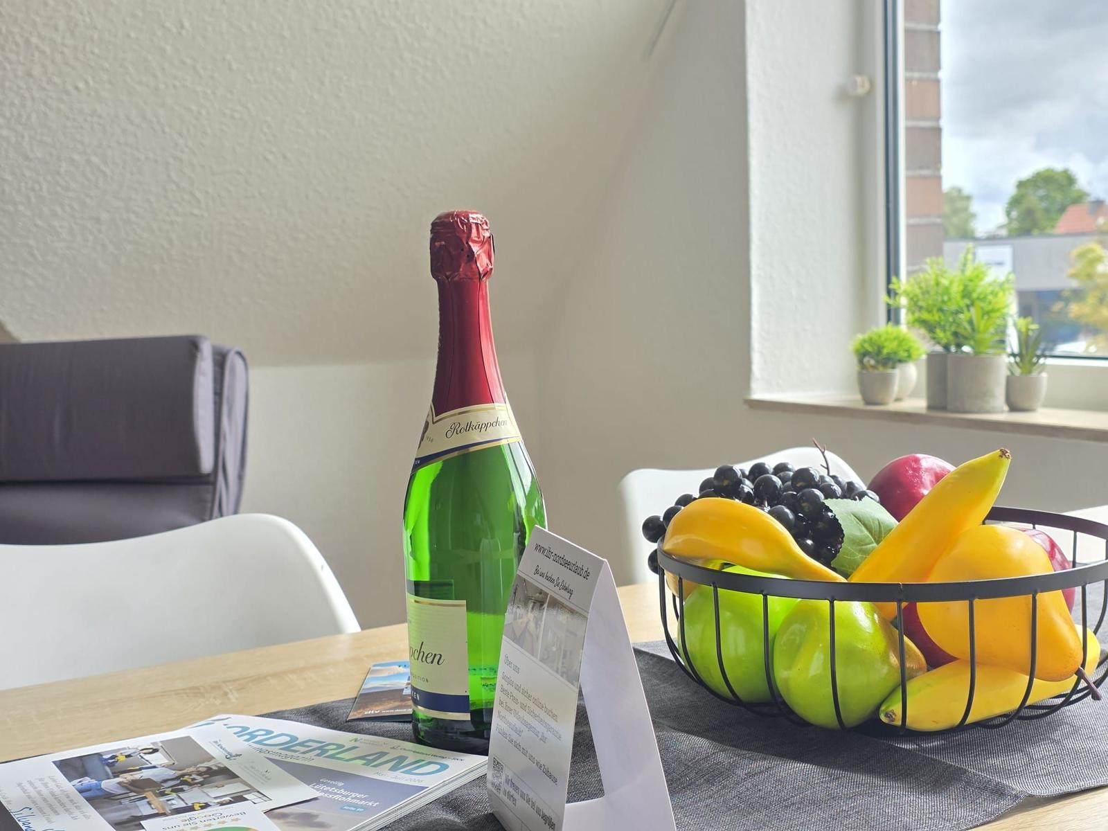 Table with bottle, fruit bowl, and brochures by window