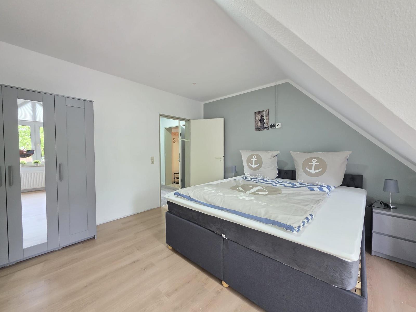 Bedroom with double bed, wardrobe, and nightstand under sloped ceiling.