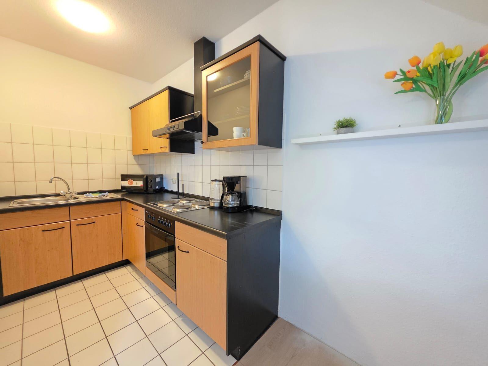 Kitchen with wooden cabinets, stove, sink, and flowers on the wall