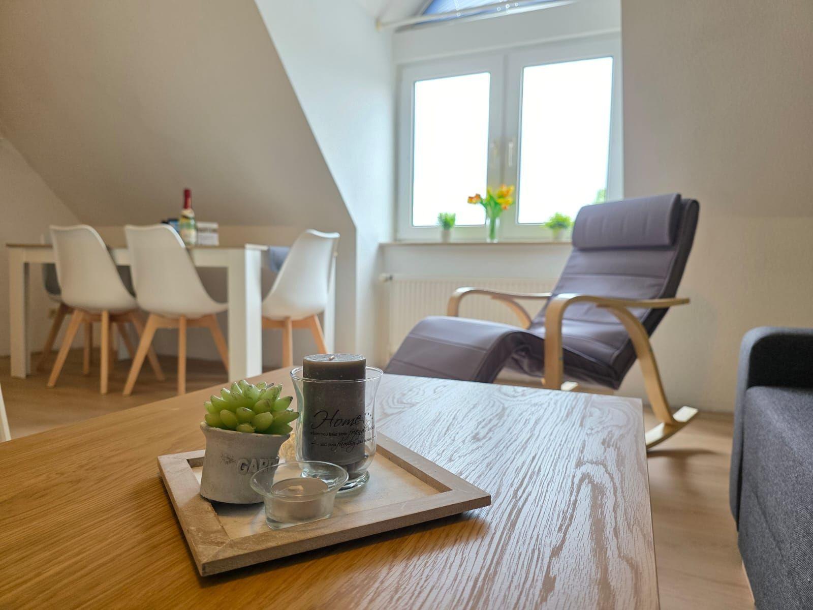 Dining area with table and chairs, a chair, and a window with flowers.