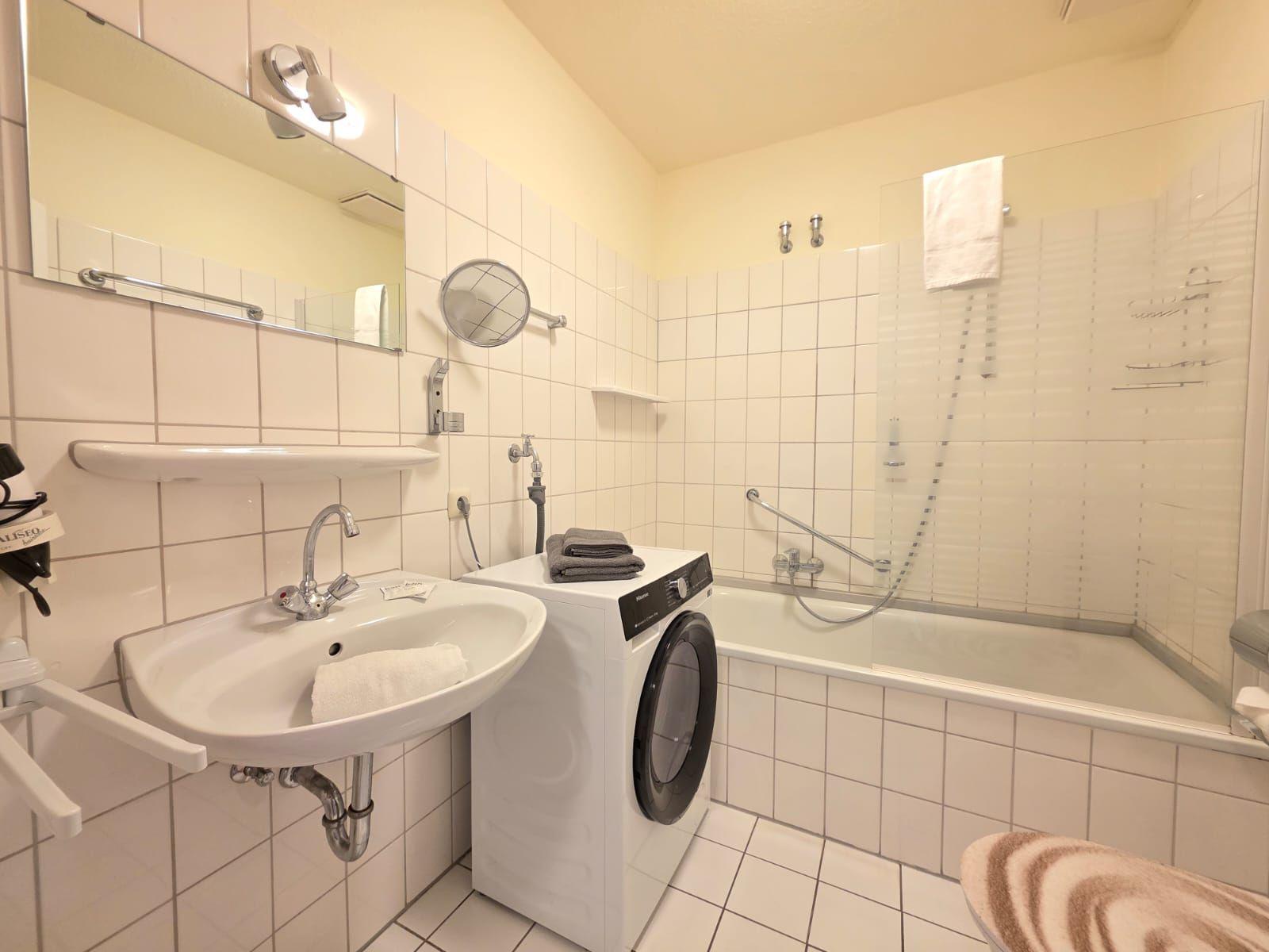 Bathroom with washing machine, shower, and mirror