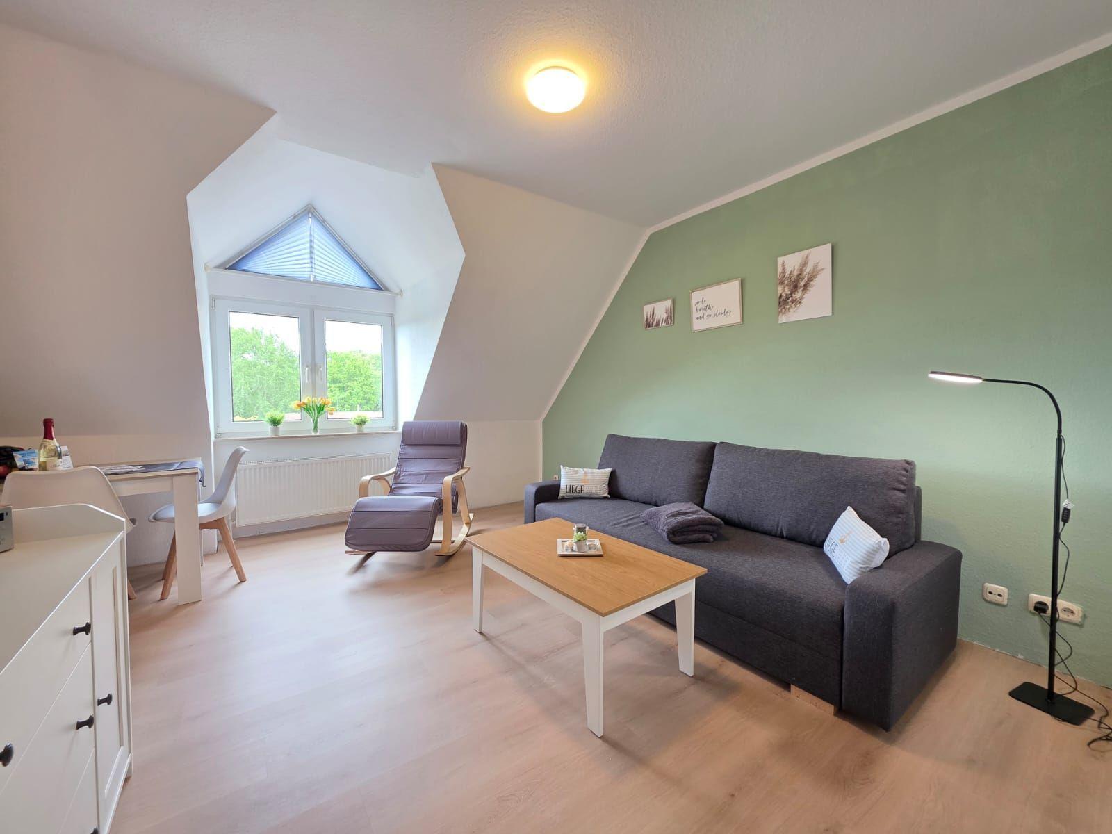 Living room with sofa, coffee table, and rocking chair under sloped ceilings.