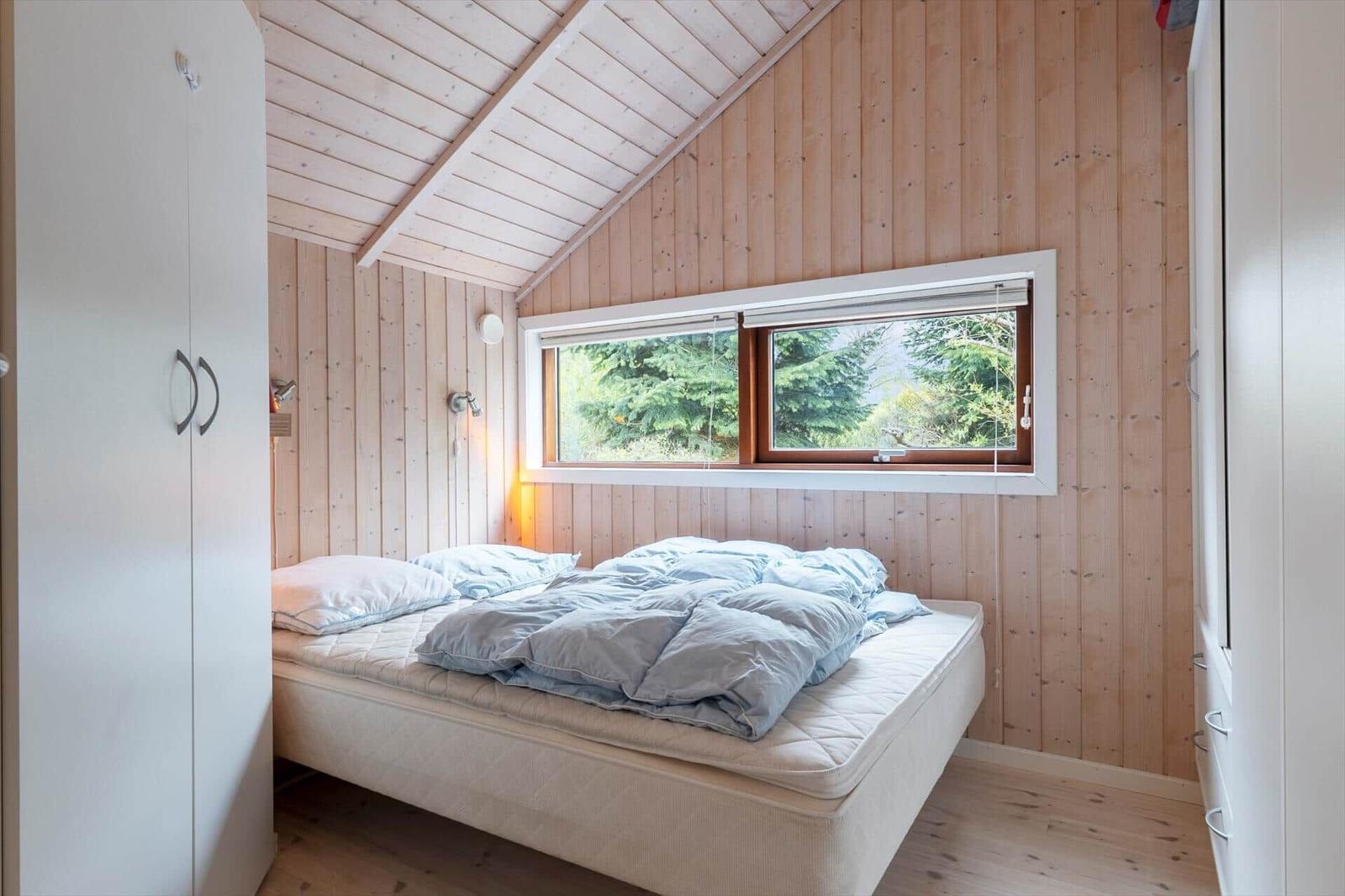 Bedroom with bed, window, and wooden wall