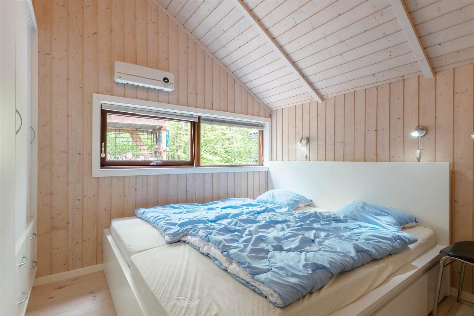 Bedroom with wooden walls, bed, and window to the garden
