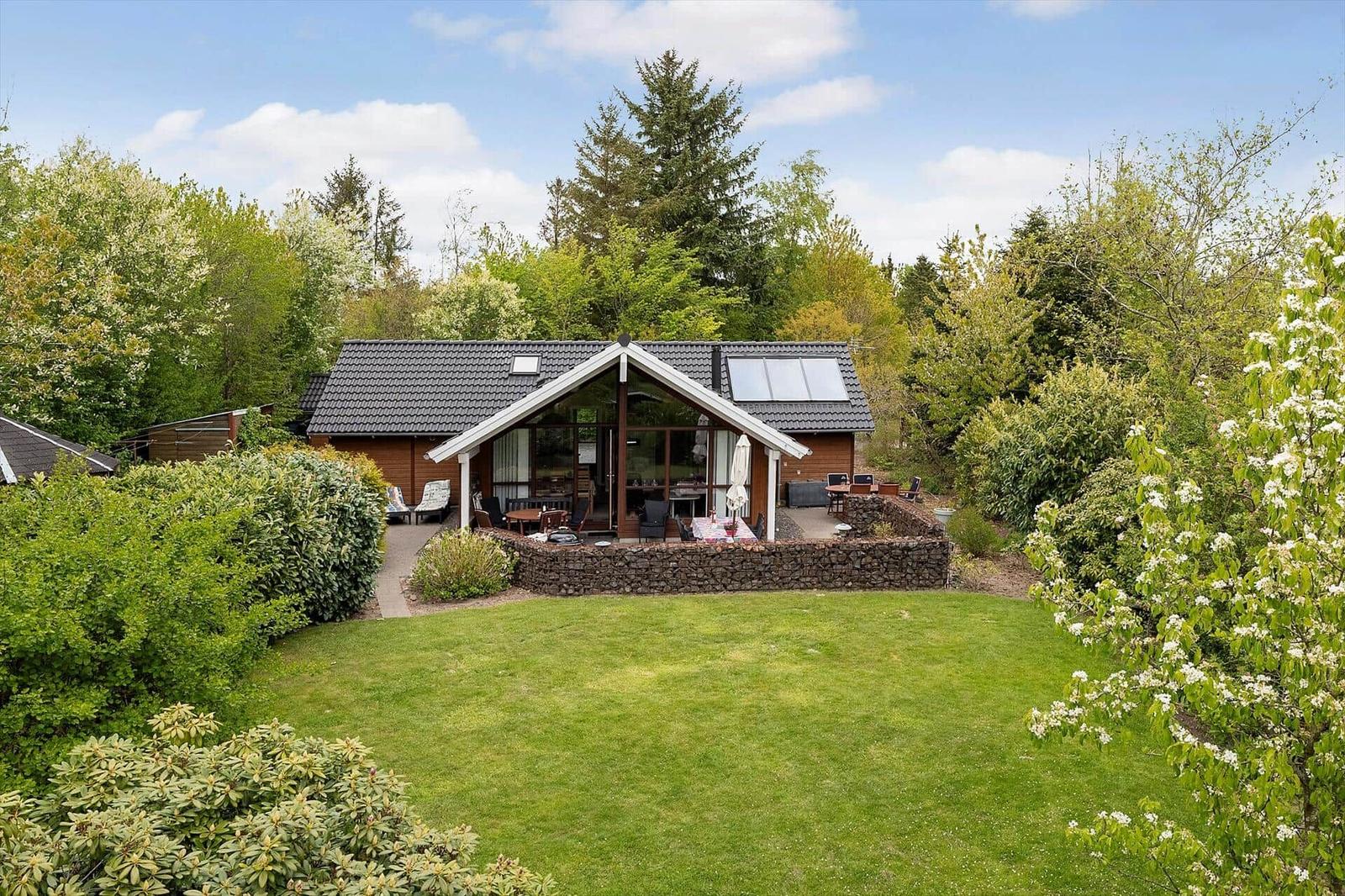 A wooden house with a large garden and terrace in the greenery.
