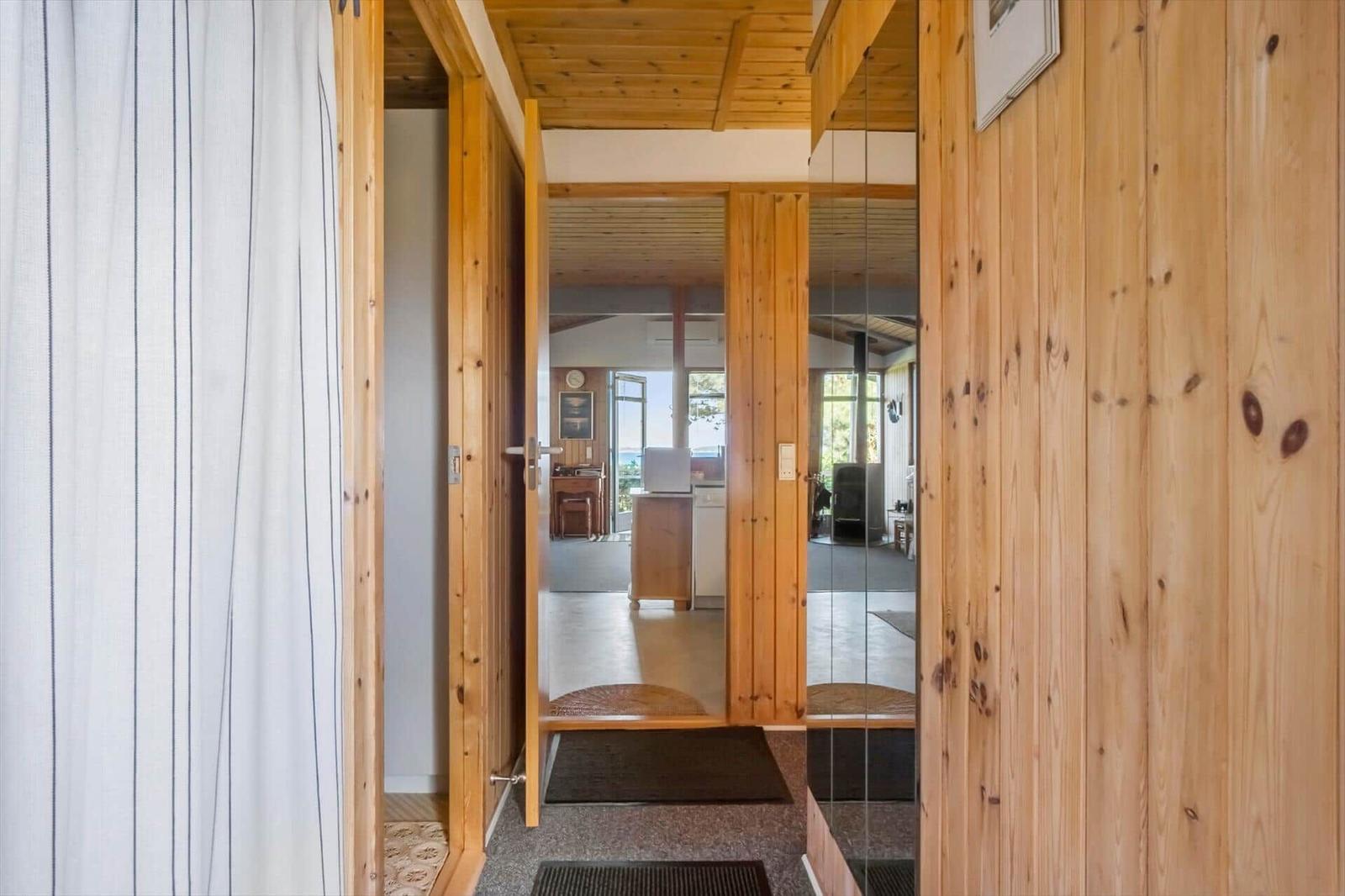 Wood-paneled entryway with view into kitchen and living area.