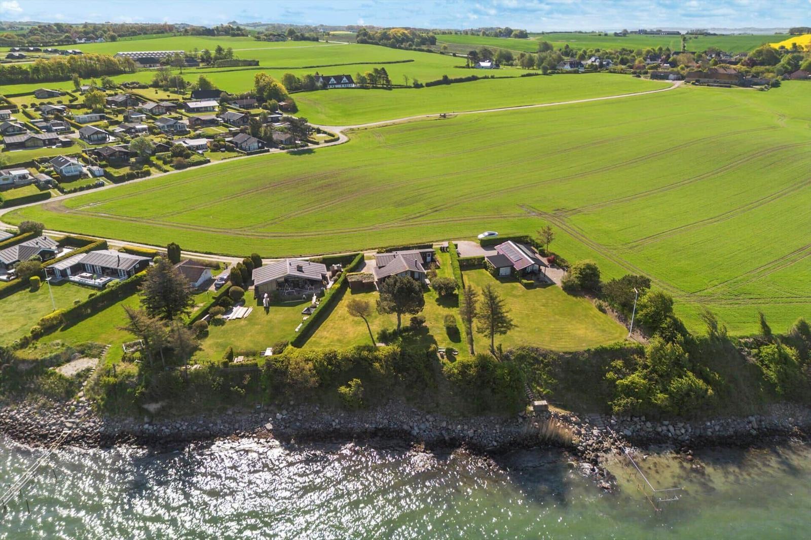 House with garden by the coast, surrounded by green fields and paths.