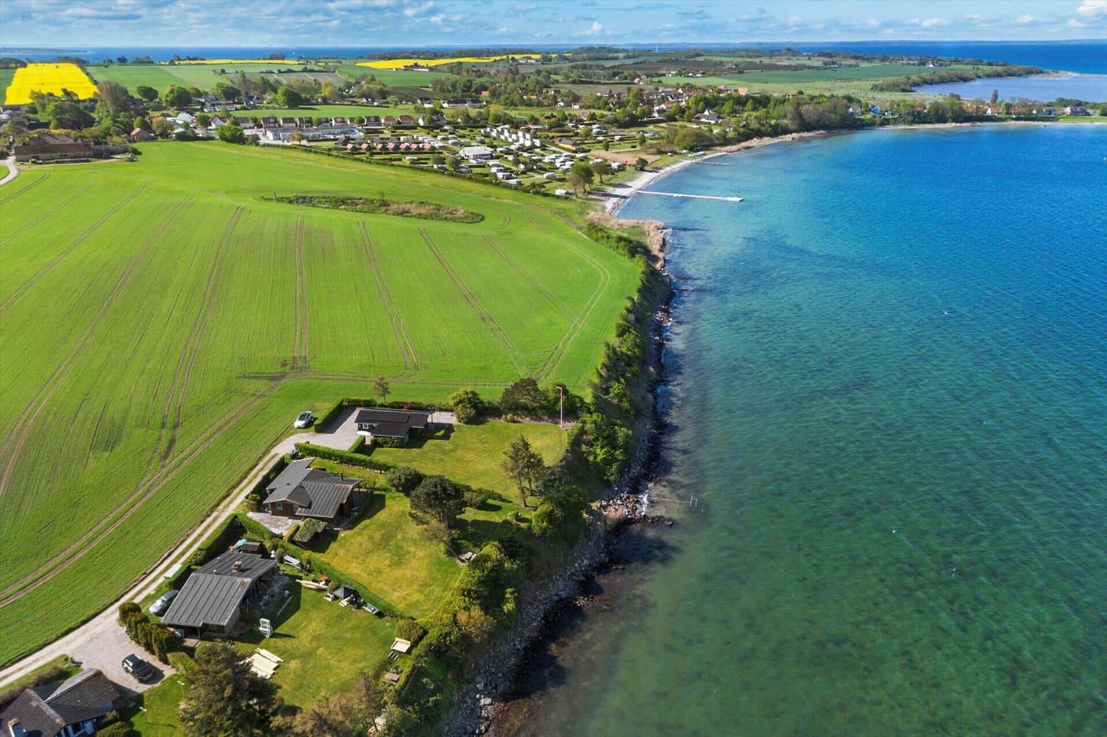 House by the coast with view of the sea and green fields.