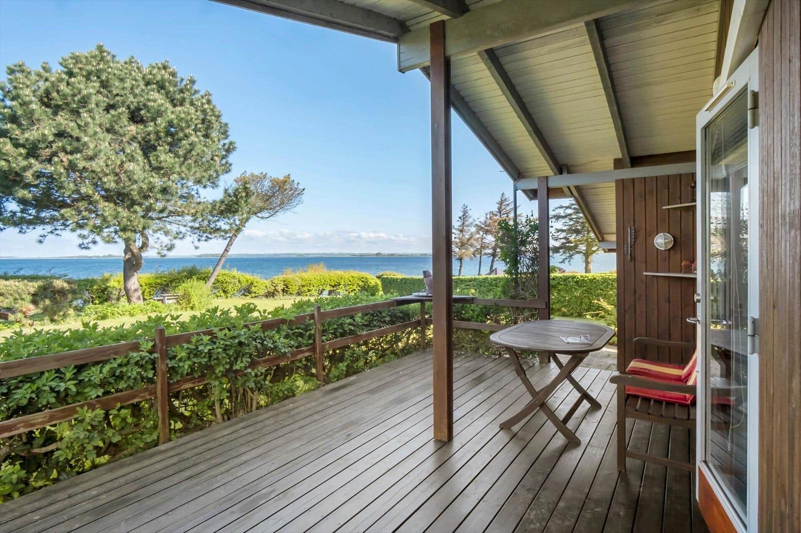 Deck with table and chair, view of water and trees.
