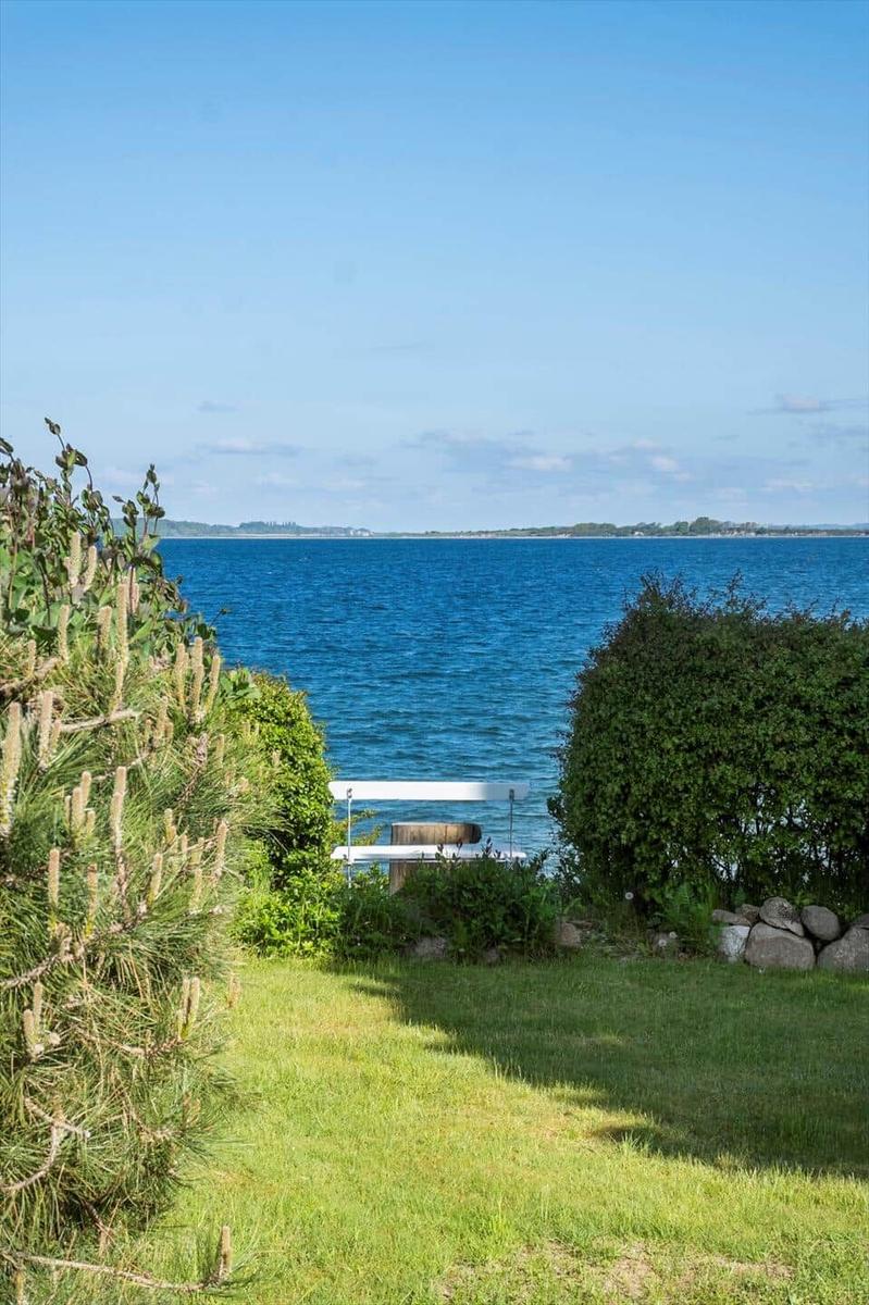 Green garden with view of the blue sea and a white wooden chair.