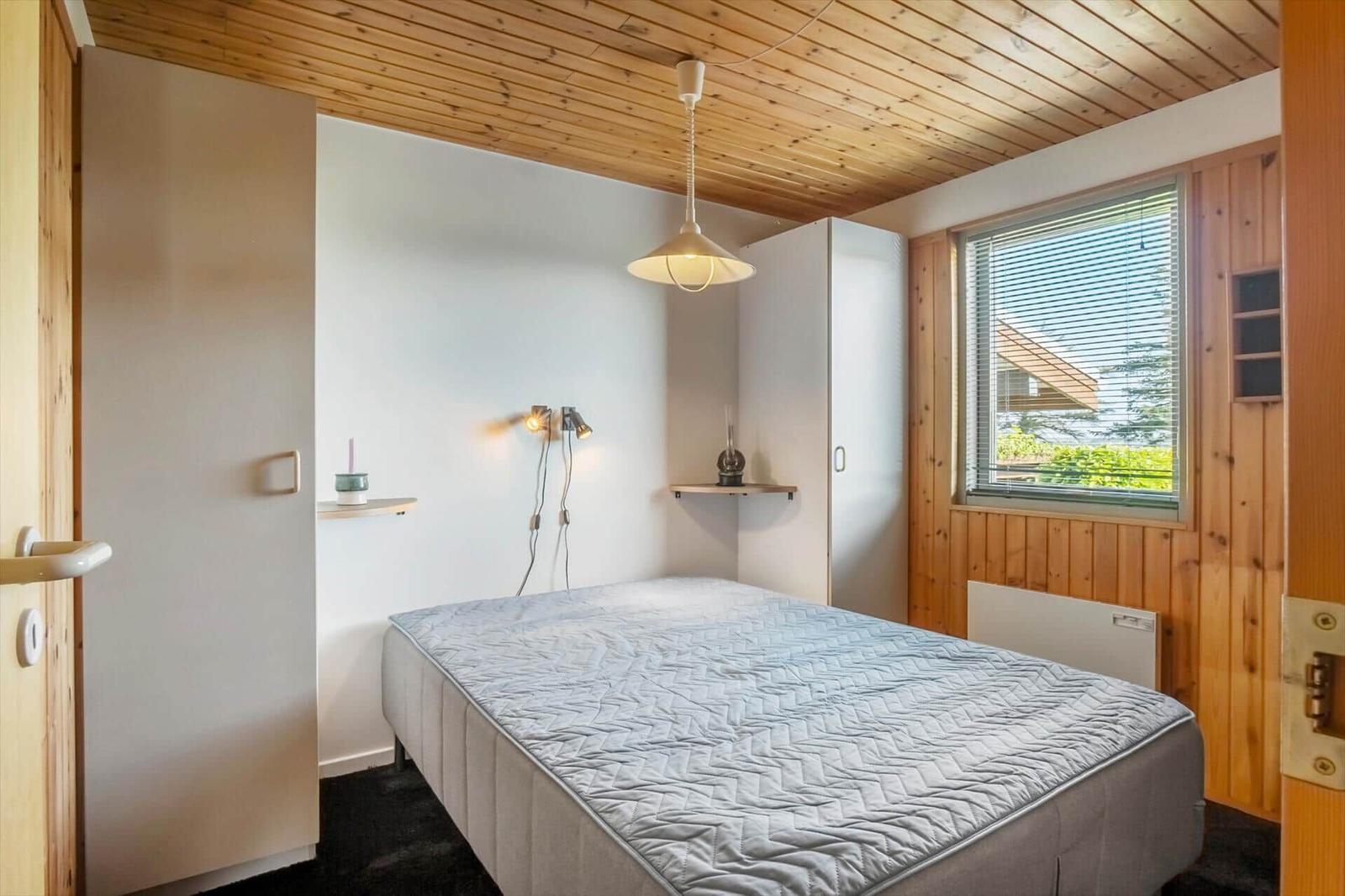 Bedroom with bed, wooden ceiling, and window with blinds.