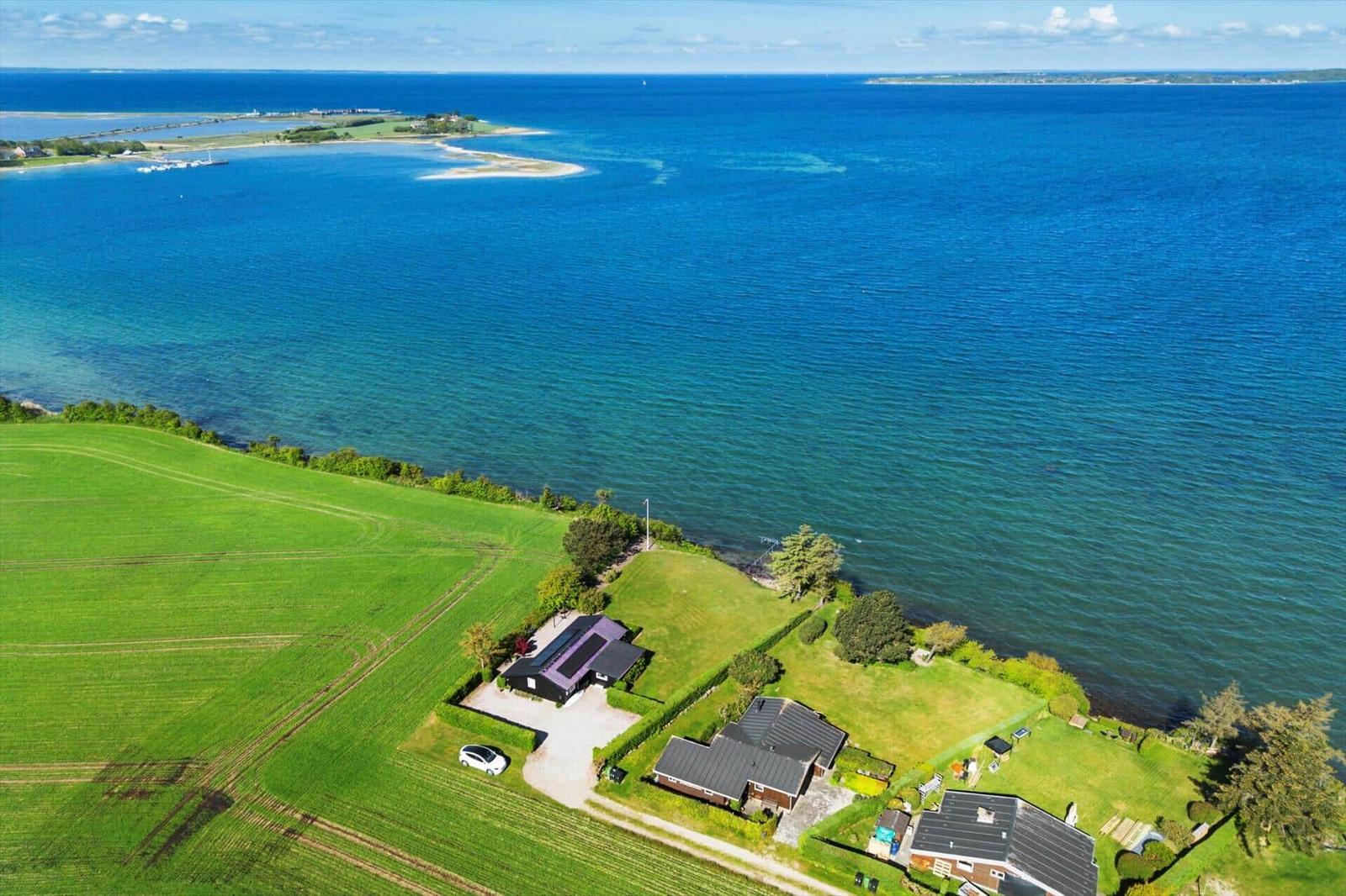House by the sea with green field and view of the island.