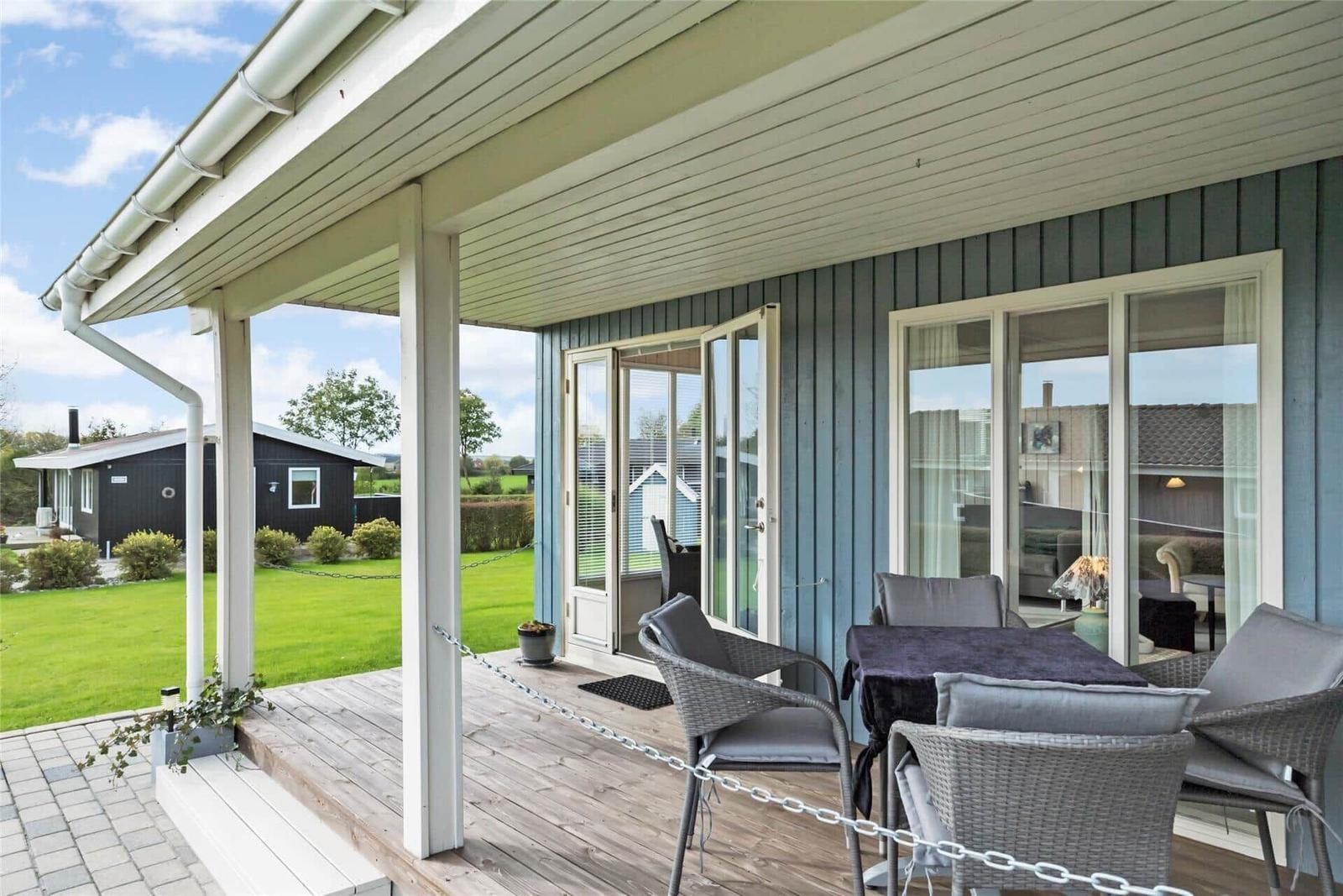 Terrasse mit Sitzgruppe, Tisch und Blick auf Garten und Ferienhaus.