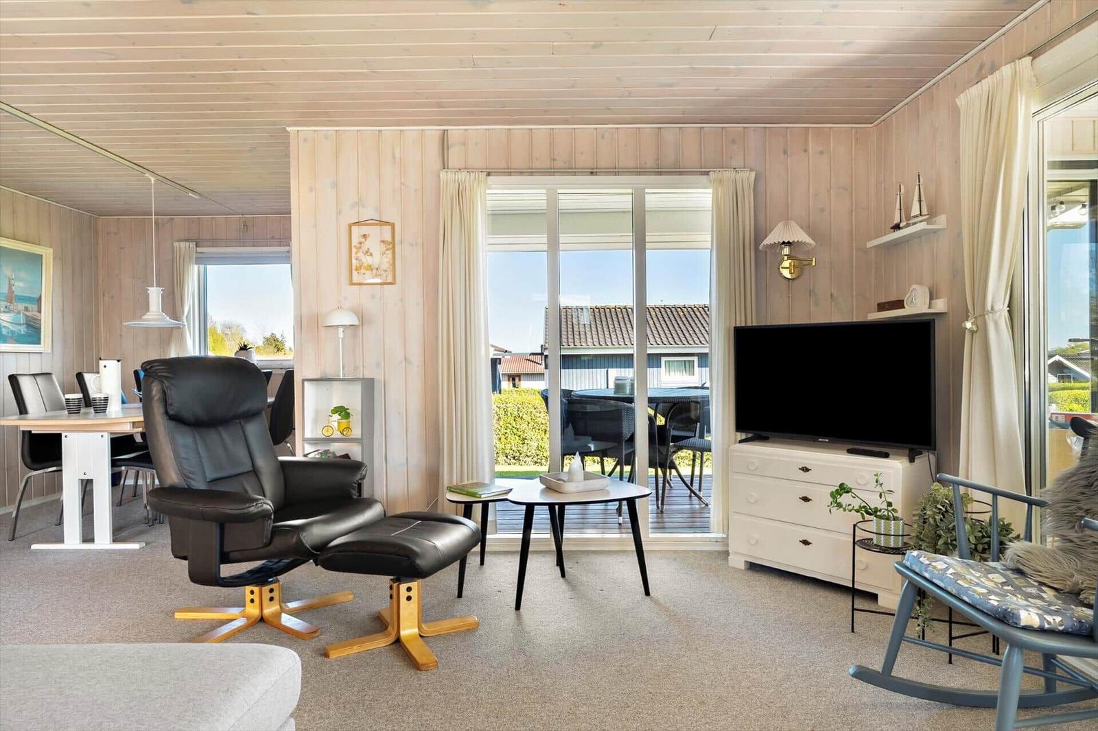 Wohnzimmer mit Sessel, Fernseher und Blick auf Terrasse