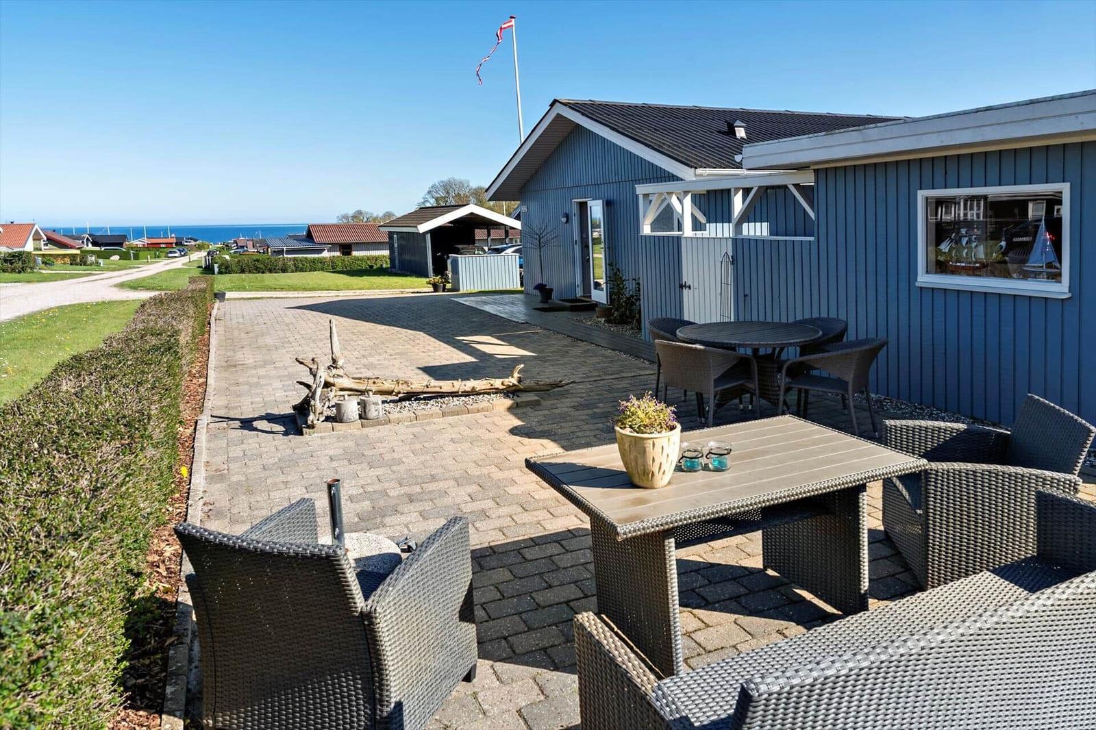 Blauer Holzhaus mit Terrasse, Garten und Blick aufs Meer.