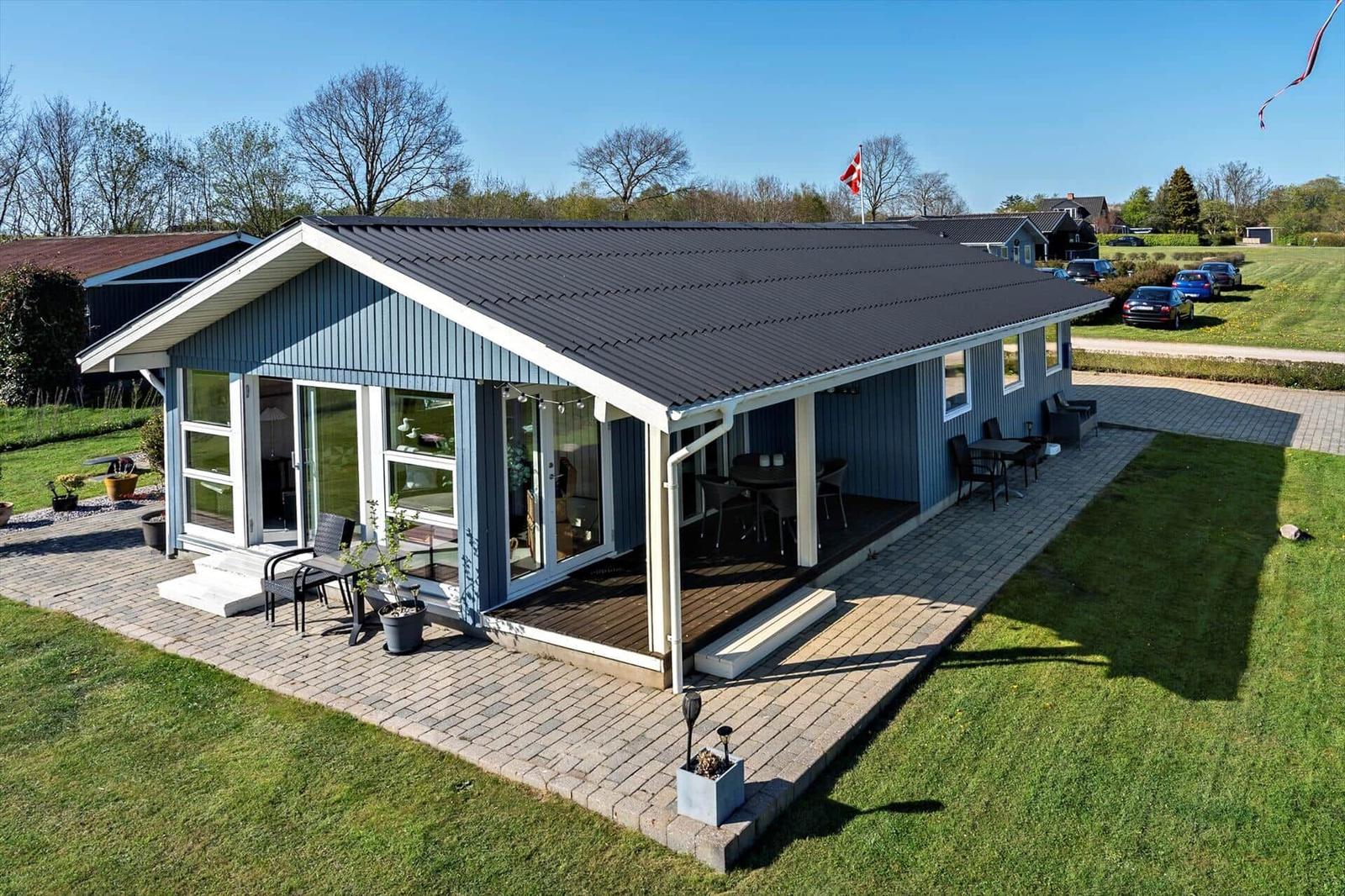 Moderne Villa mit Terrasse und Garten. Flagge weht im Wind.