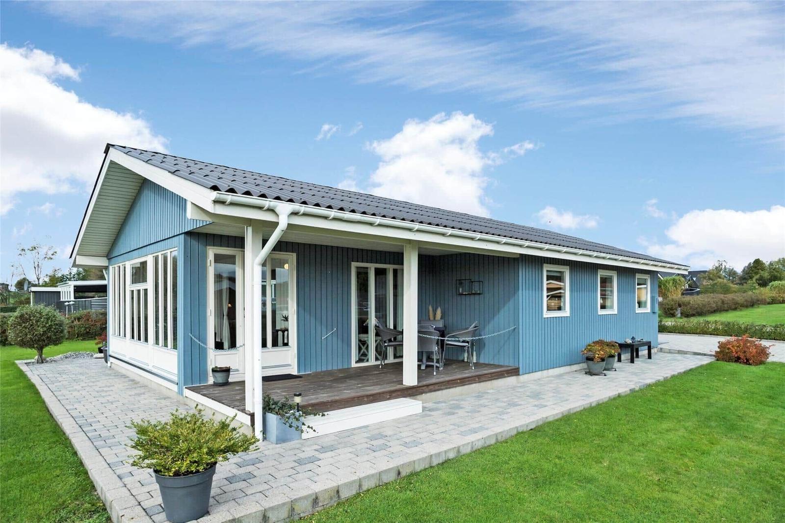 Blau gestrichenes Haus mit Terrasse und Garten. Modernes Design mit weißen Fensterrahmen.