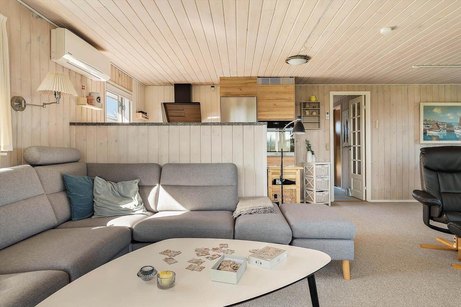 Wohnbereich mit Sofa, Couchtisch und Küchenbereich im Hintergrund.