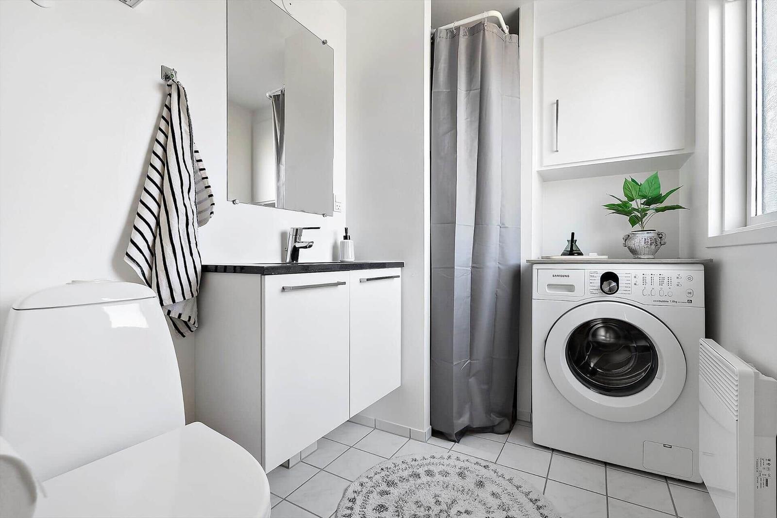 Badezimmer mit Waschmaschine, Dusche und Spiegelschrank.